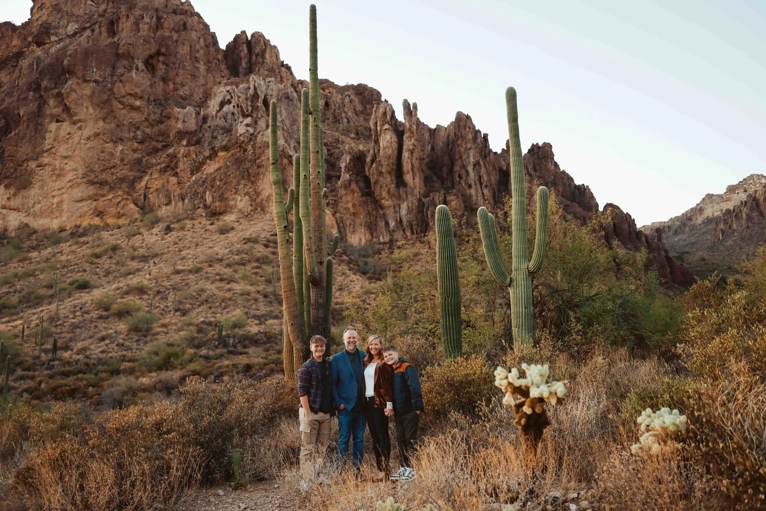 Family of four surrounded by saguaro cacti at Superstition Mountain session