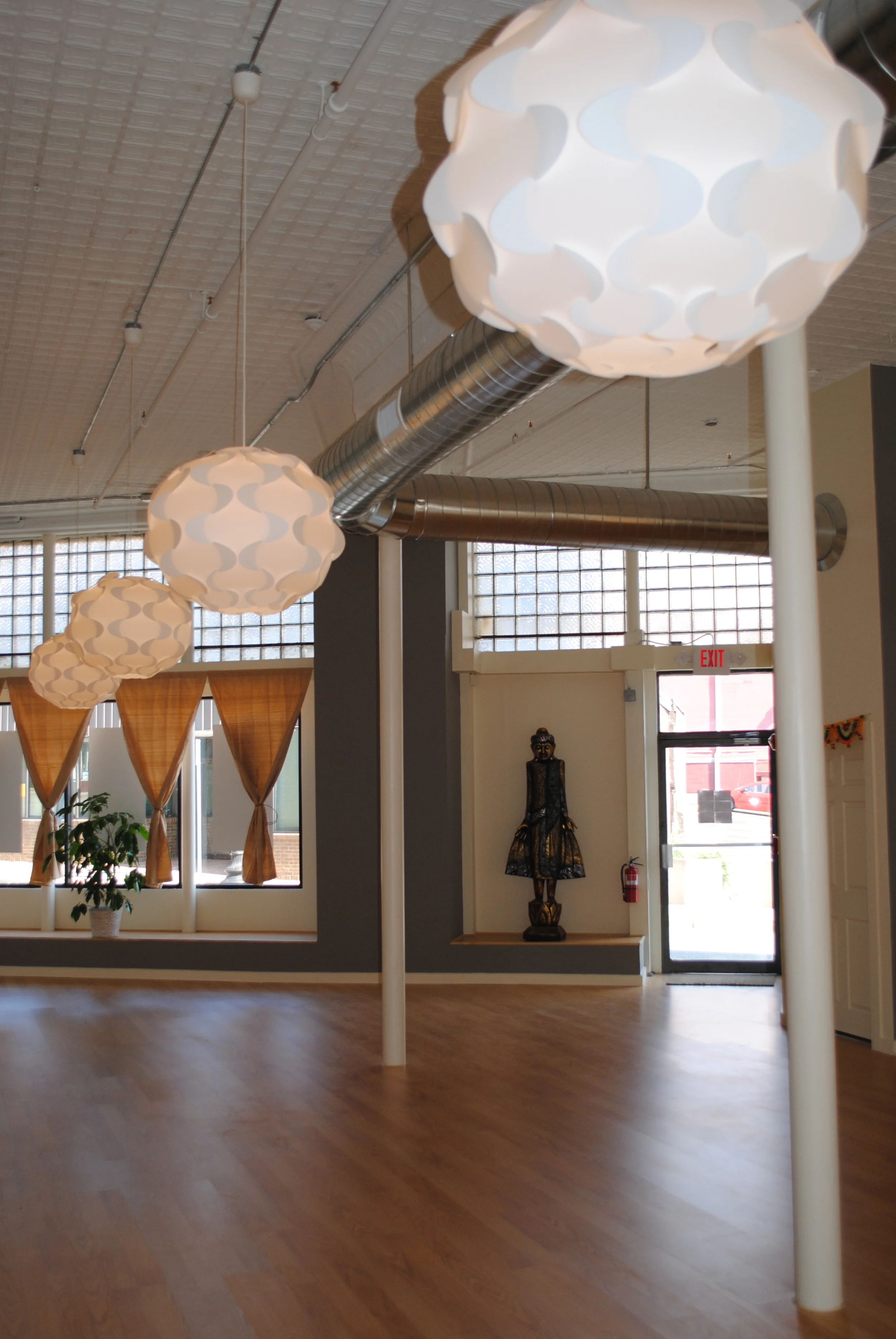 Studio The beauty of the space is told through the block glass above the studio floor. This 6-foot tall Buddah was also a purchase from Warren, RI. Here you can see the original tin ceiling Alison had painted in the brightest white she could find. The walls are navajo white and dovetail gray, both by Benjamin Moore. The curtains in the back hang from the same plumbing pipe material used to build the studio room dividers. The lanterns (an upgrade from paper lanterns) were a quick but efficient "get" from Ikea. 