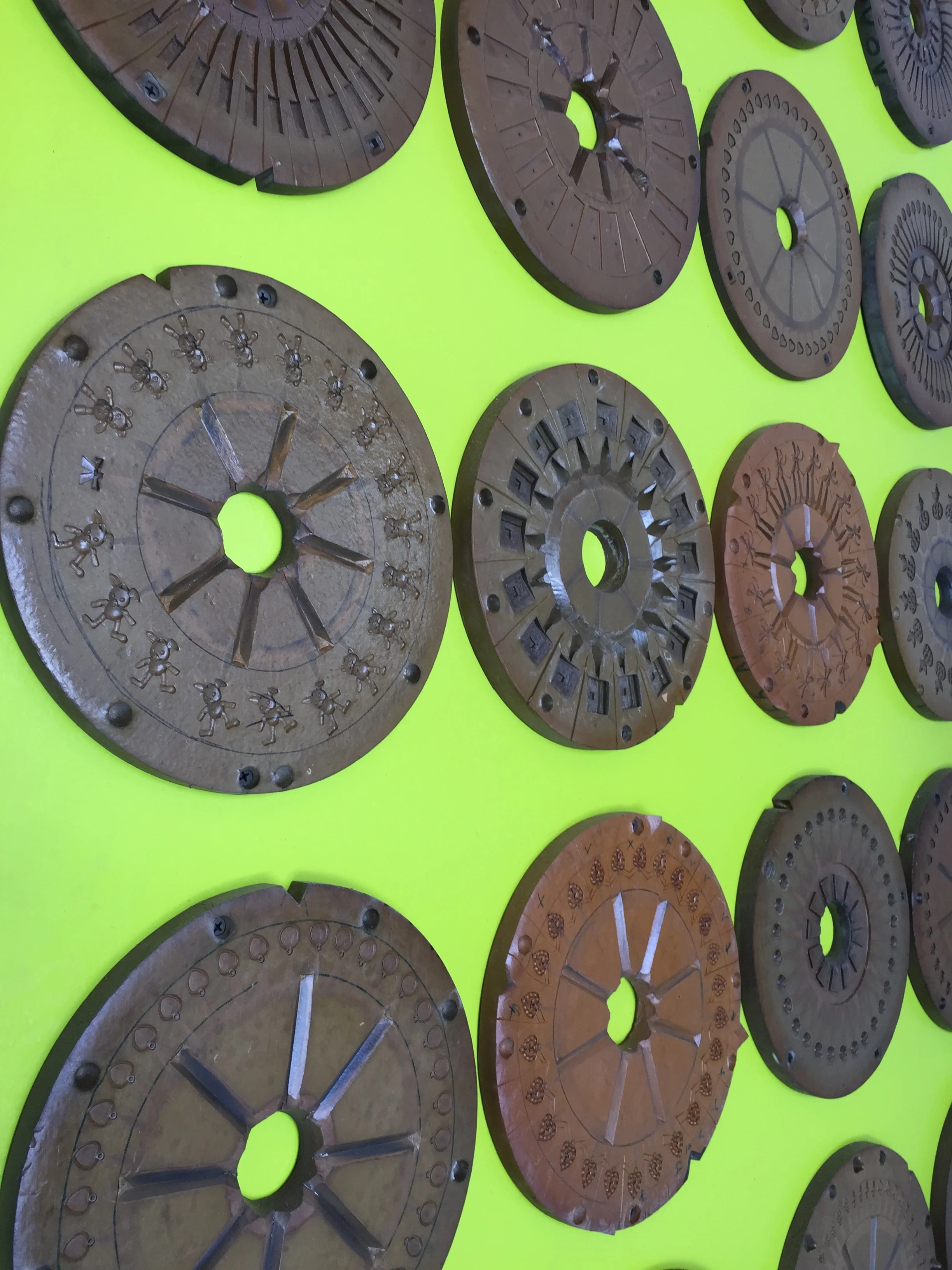 These are old jewelry molds Alison found in an old, Pawtucket mill. She collected them, each with different patterns, and cleaned them up. On top of a bright, lime green wooden screen, hanging on plumbing pipe frames, these serve to hide the outdoor fridge and pool equipment.