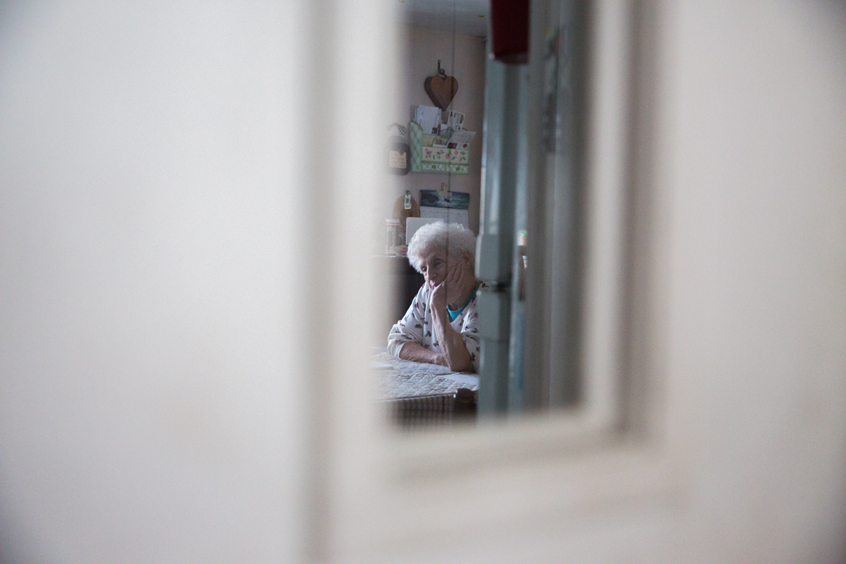 June Weeks sits in her kitchen in Mexico, Maine while her husband Clayton Weeks, who is dying from lung cancer, has his weekly visit with his hospice nurse.