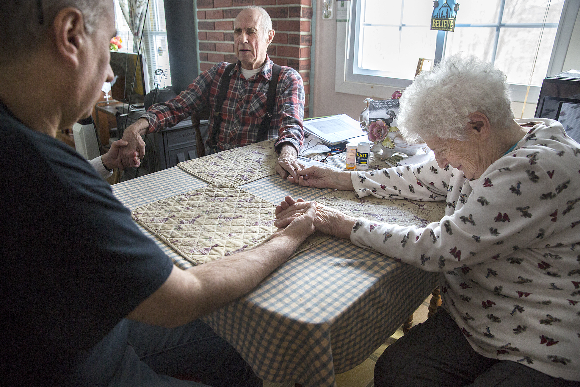 Clayton Weeks, 81, (center) was diagnosed with lung cancer in November 2014. In January with a diagnosis of six or less months to live, Clayton decided to go in the care of Androscoggin Home Care and Hospice. Clayton's wife June, son Clayton and an Androscoggin Hospice Chaplin Dick Waddell, hold hand in prayer at the Week's home in Mexico, Maine, a few weeks before Clayton's passing. 