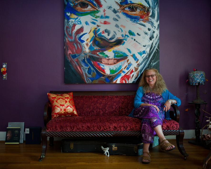 Founder and Executive Director of Artists for World Peace (or AFWP), Wendy Black-Nasta, sits in her home office in Middletown, CT, under a painting of Kamar Thomas, a Wesleyan Alum, who received a fine arts scholarship from AFWP and gifted five paintings back to the organization to be sold to help fund more art scholarships. AFWP is an organization of artists and activists who promote peace by feeding, housing, educating and providing healthcare to the most vulnerable and lifting communities to a place of hope. They recently opened a health center in Africa. 