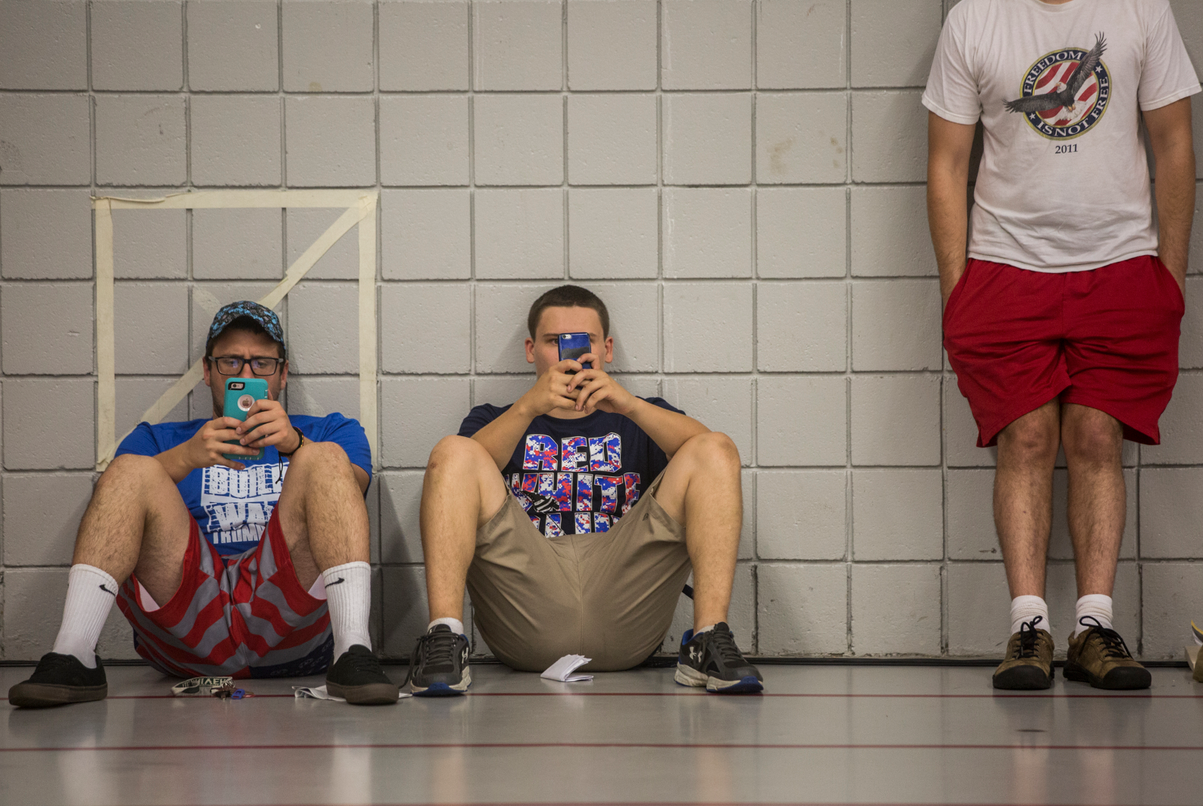 Dante Salce, 19, and Gustav Perterson, 19, of Stratford look at their iPhones as the wait for Republican Presidential Nominee Donald Trump to speak at Sacred Heart University in Fairfield, Connecticut on Saturday evening. 