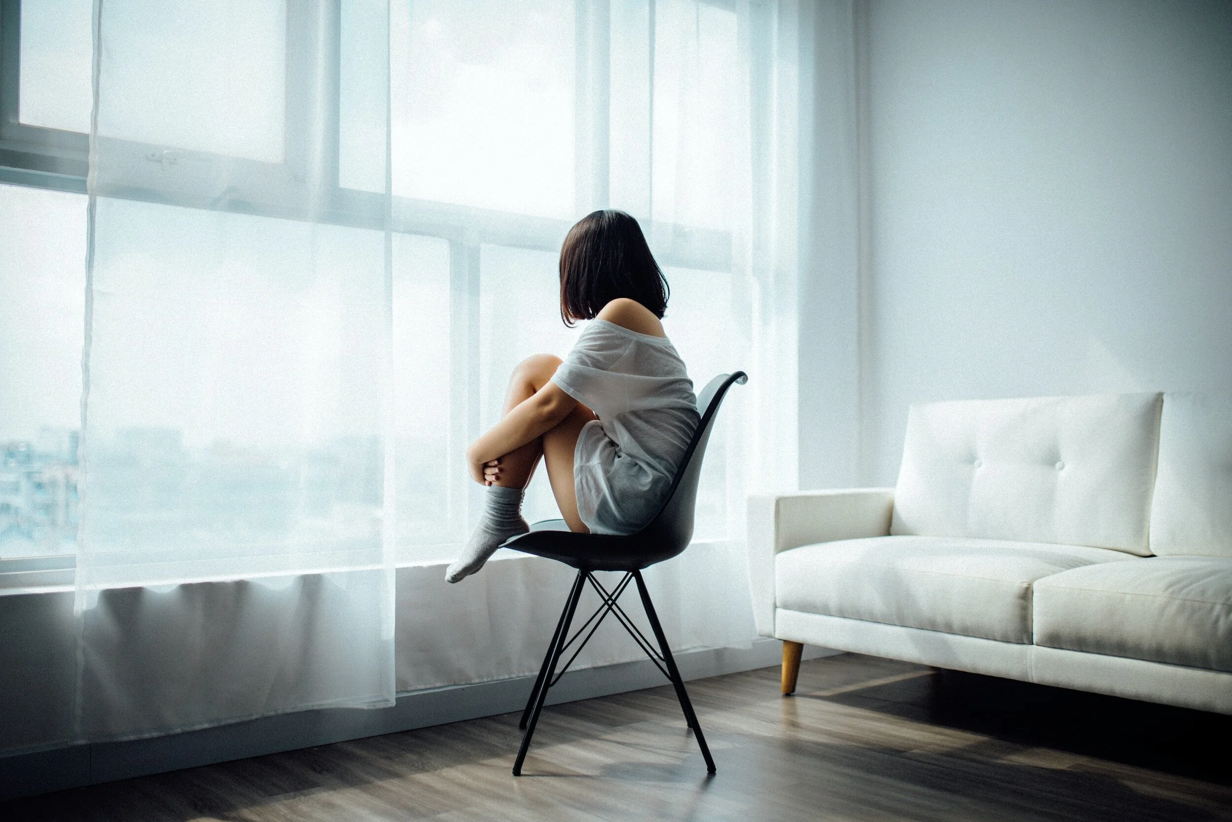 How to Stop Ruminating: depressed woman sitting in a chair, staring out the window