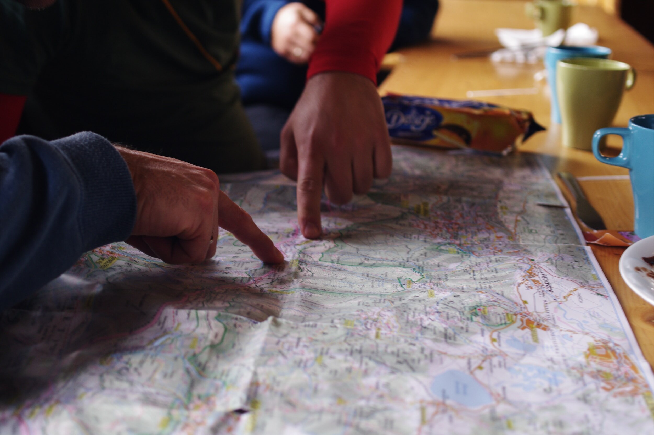 fingers of two people pointing at routes on a map