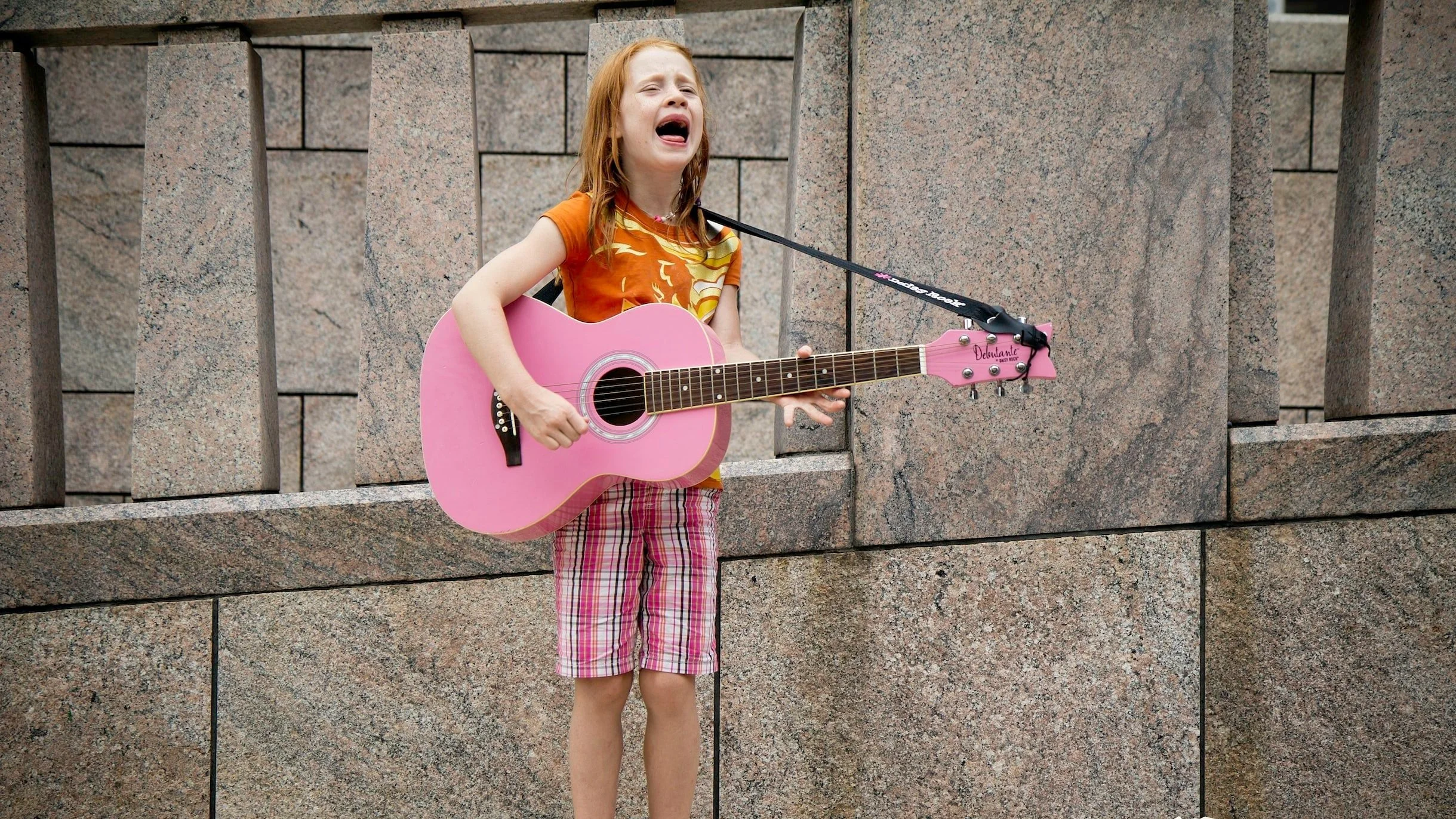 Cognitive Defusion Techniques and Exercises: A little girl engaging in a defusion exercise (singing at the top of her lungs with a pink guitar)