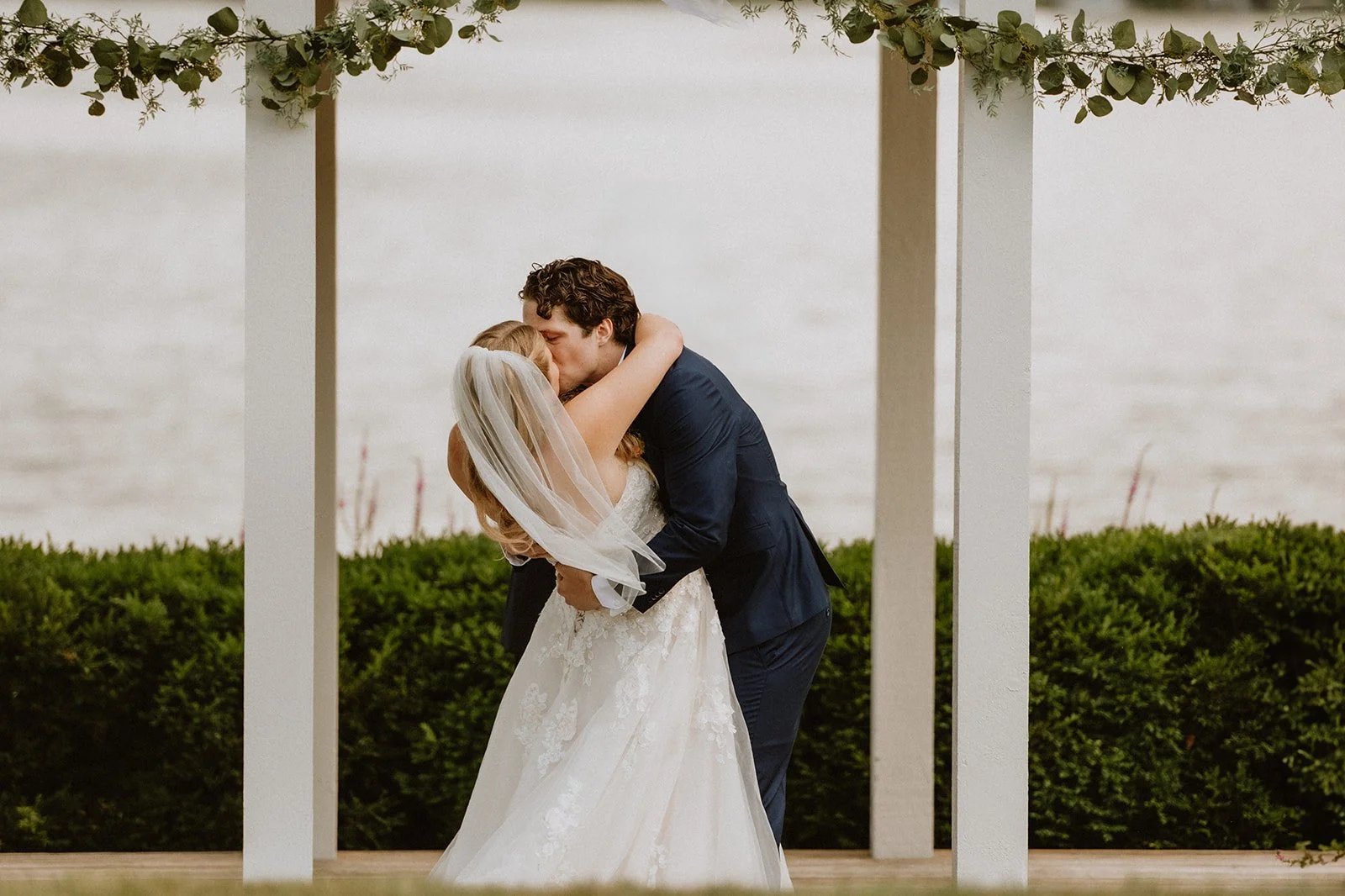 Bride and groom kissing under arch at outdoor wedding