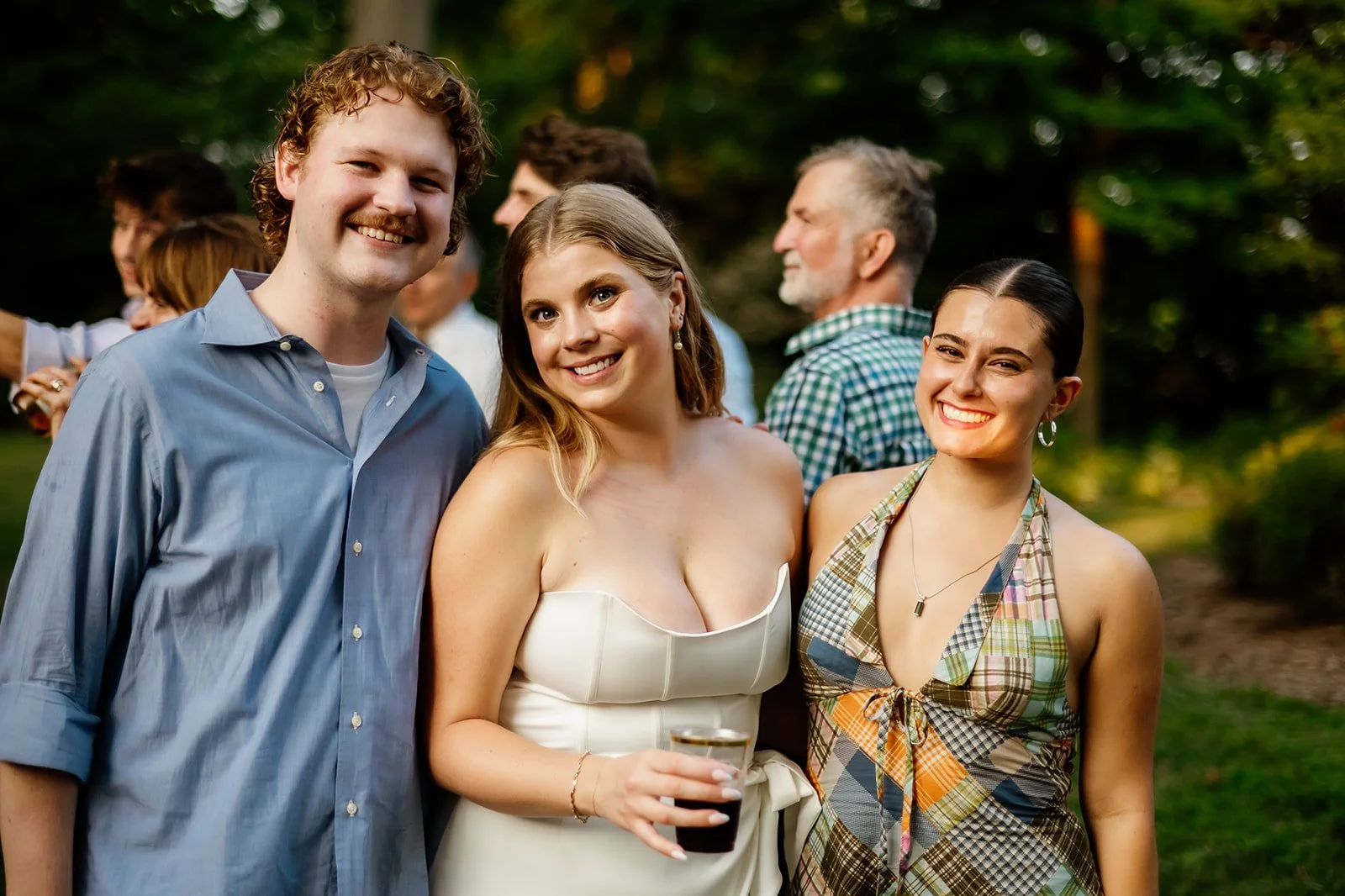 Three people smiling at an outdoor gathering.