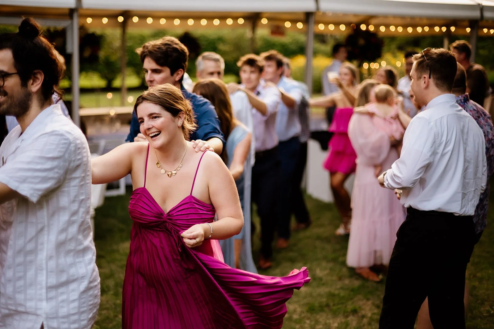 Group of people in formal attire dancing at an outdoor event.