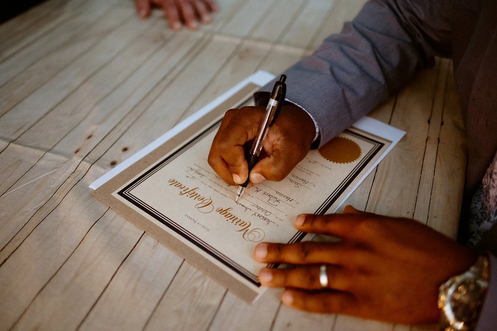 Person signing a marriage certificate on a wooden table