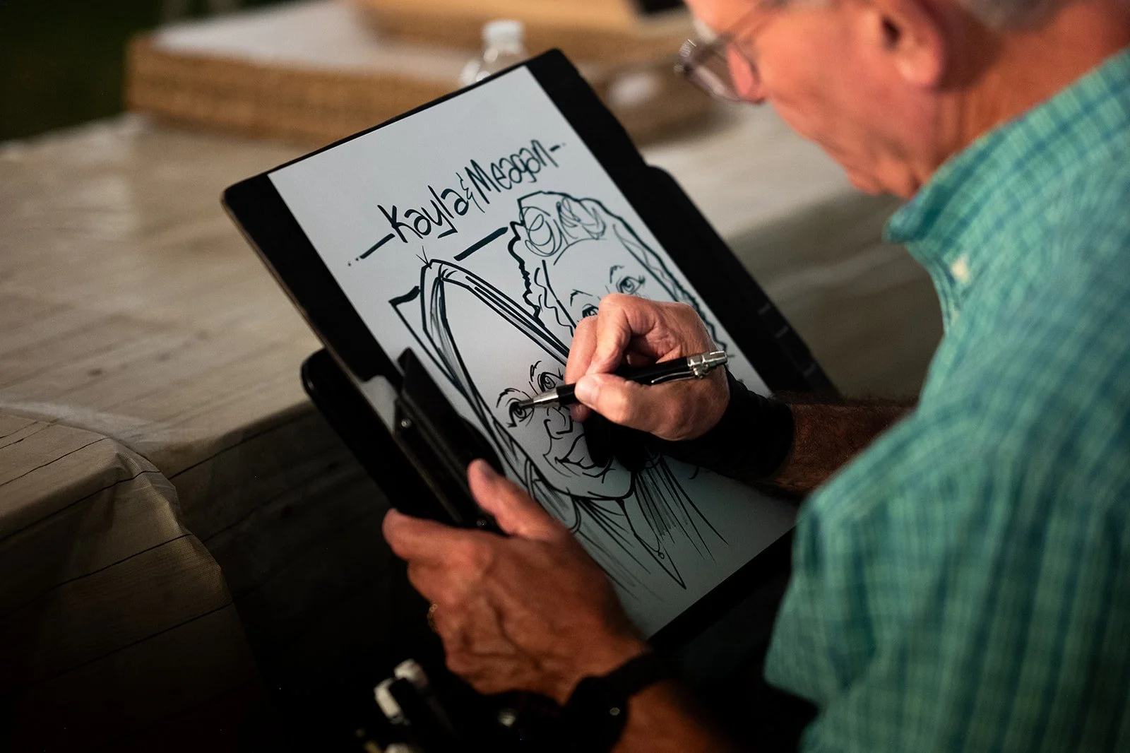 Artist drawing a caricature of two people on a clipboard.