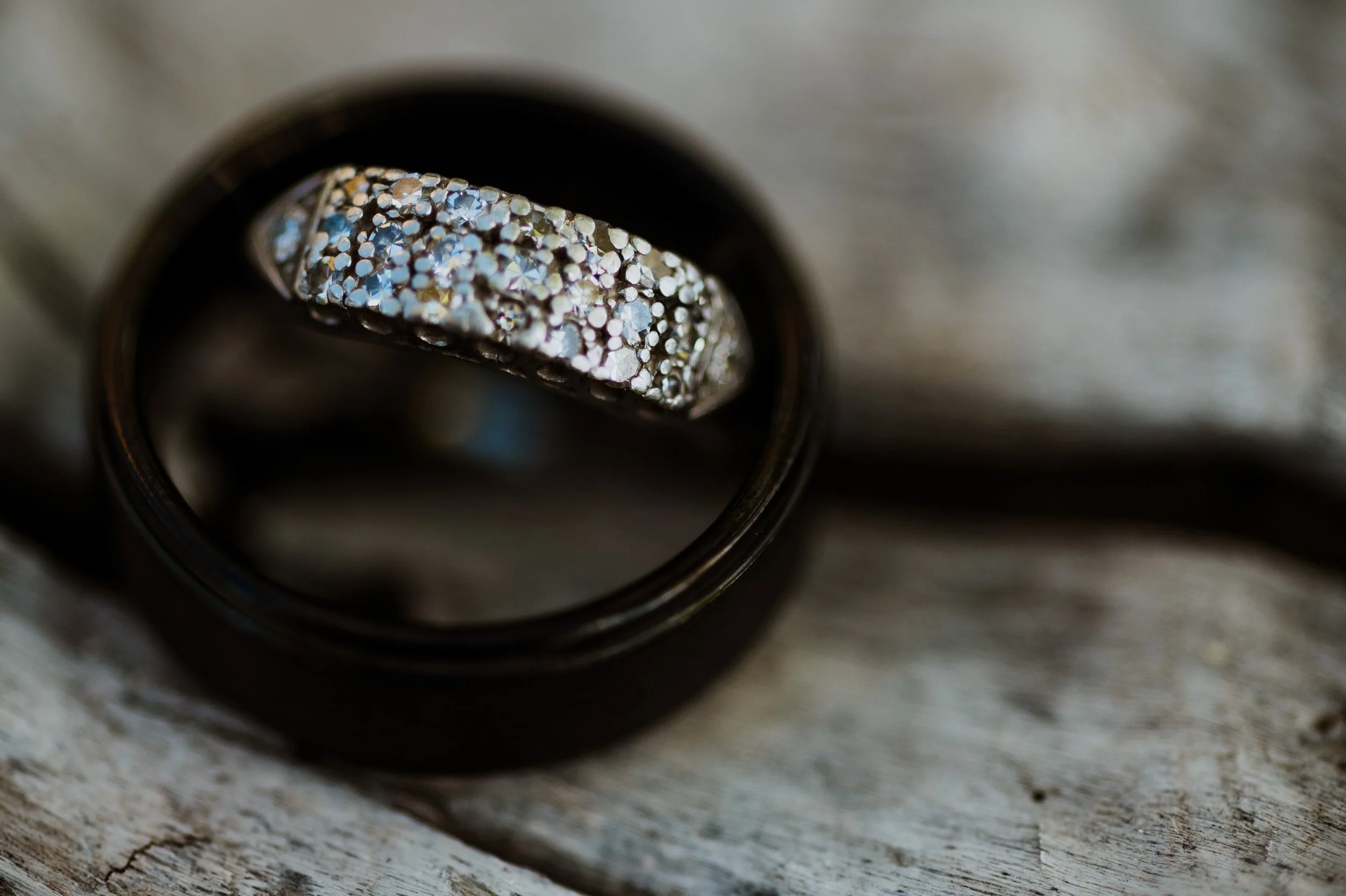 Close-up of a textured silver ring inside a black ring on a wooden surface.