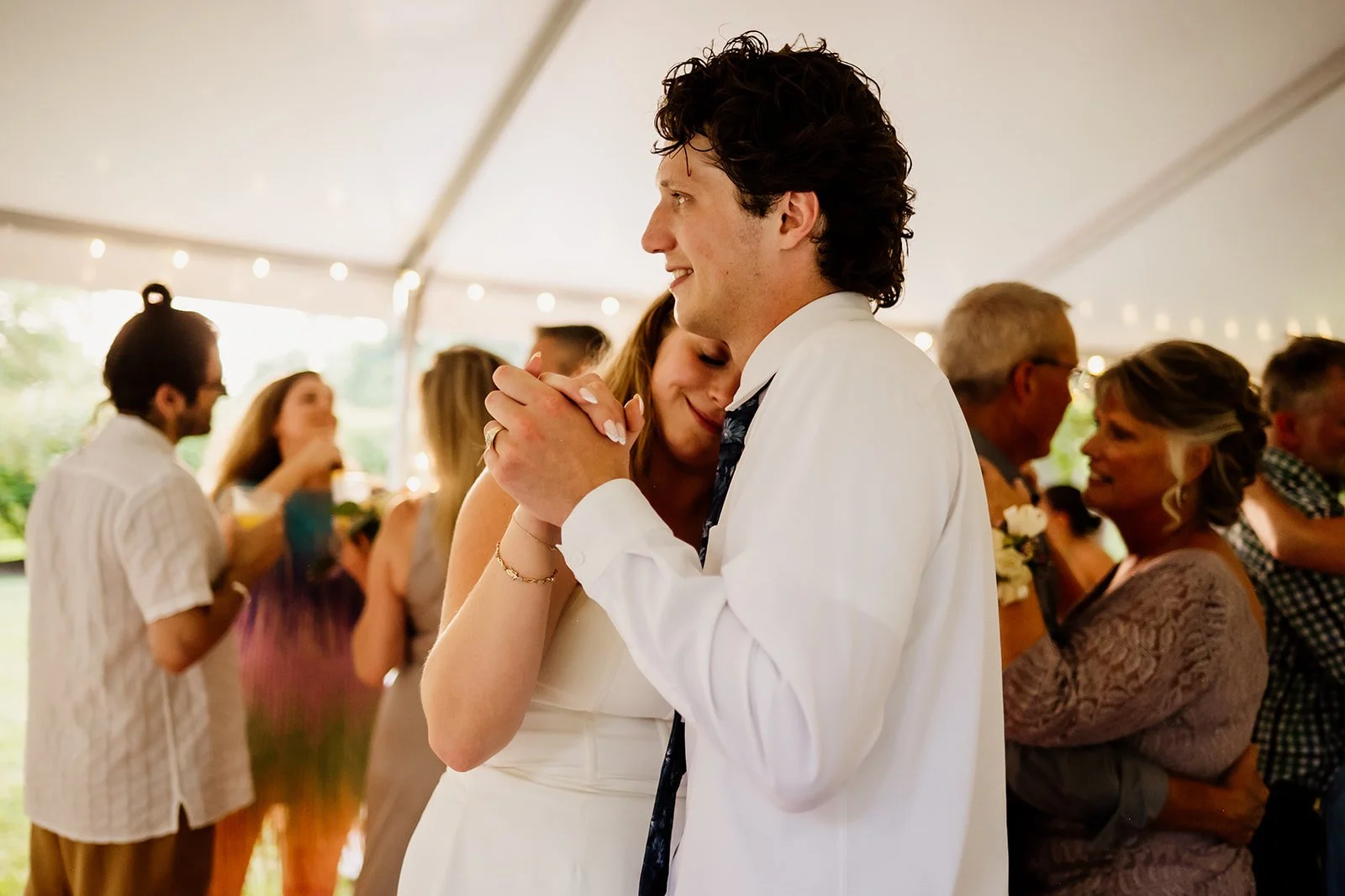 Couple dancing at a wedding with guests in the background.