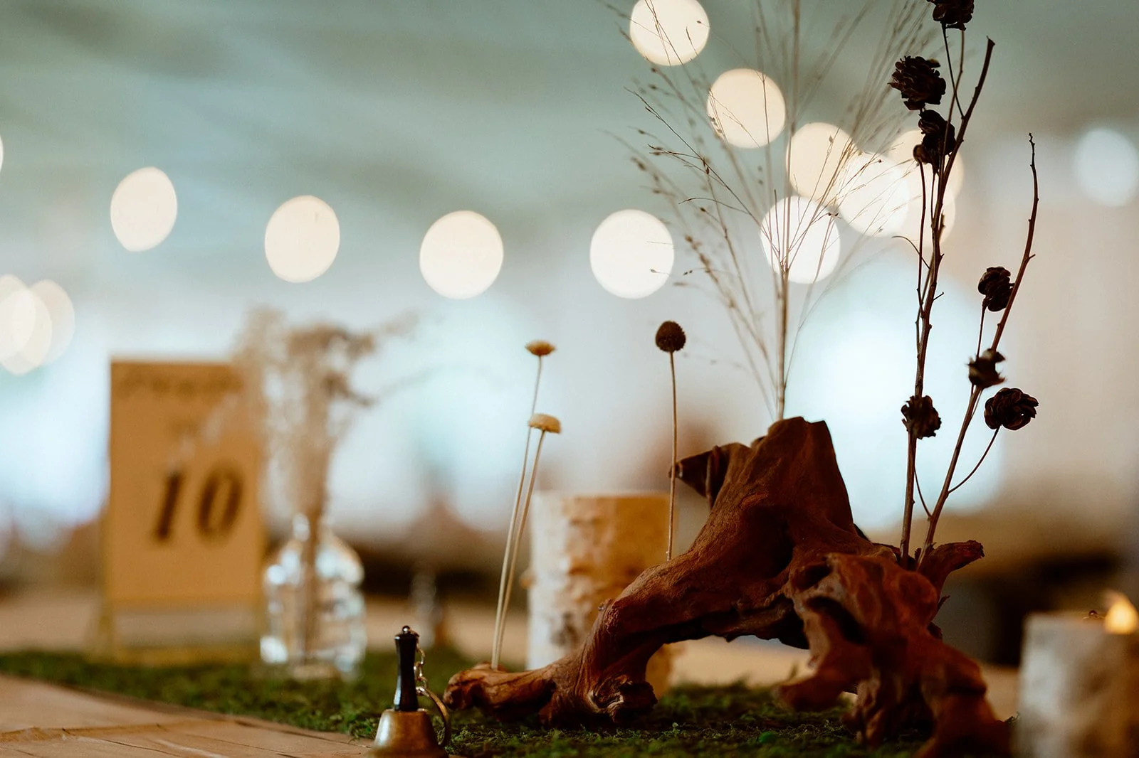 Rustic table centerpiece with dried flowers, driftwood, and candles.