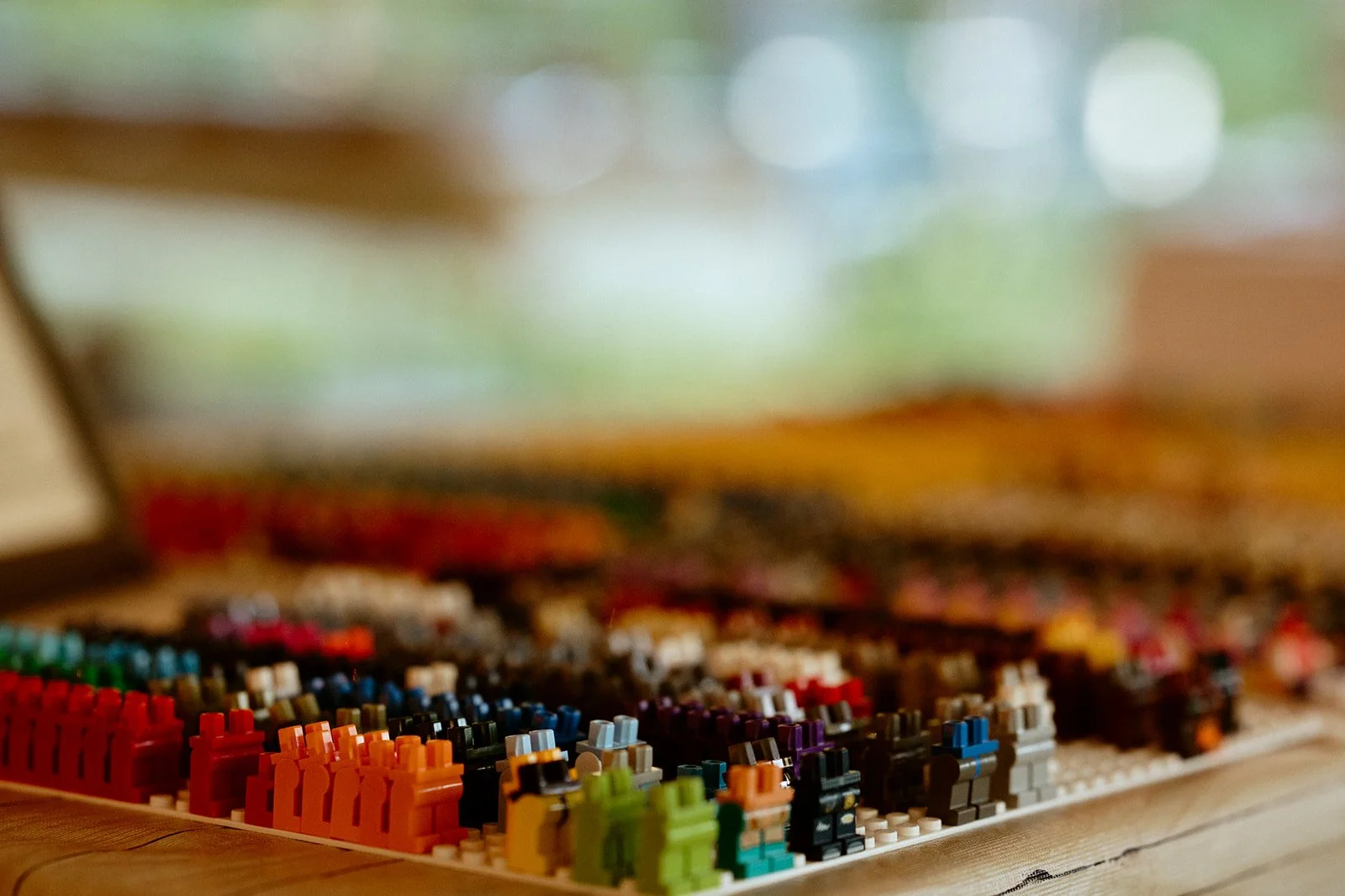 Close-up of colorful LEGO minifigure parts arranged in rows on a table, with a blurred background.