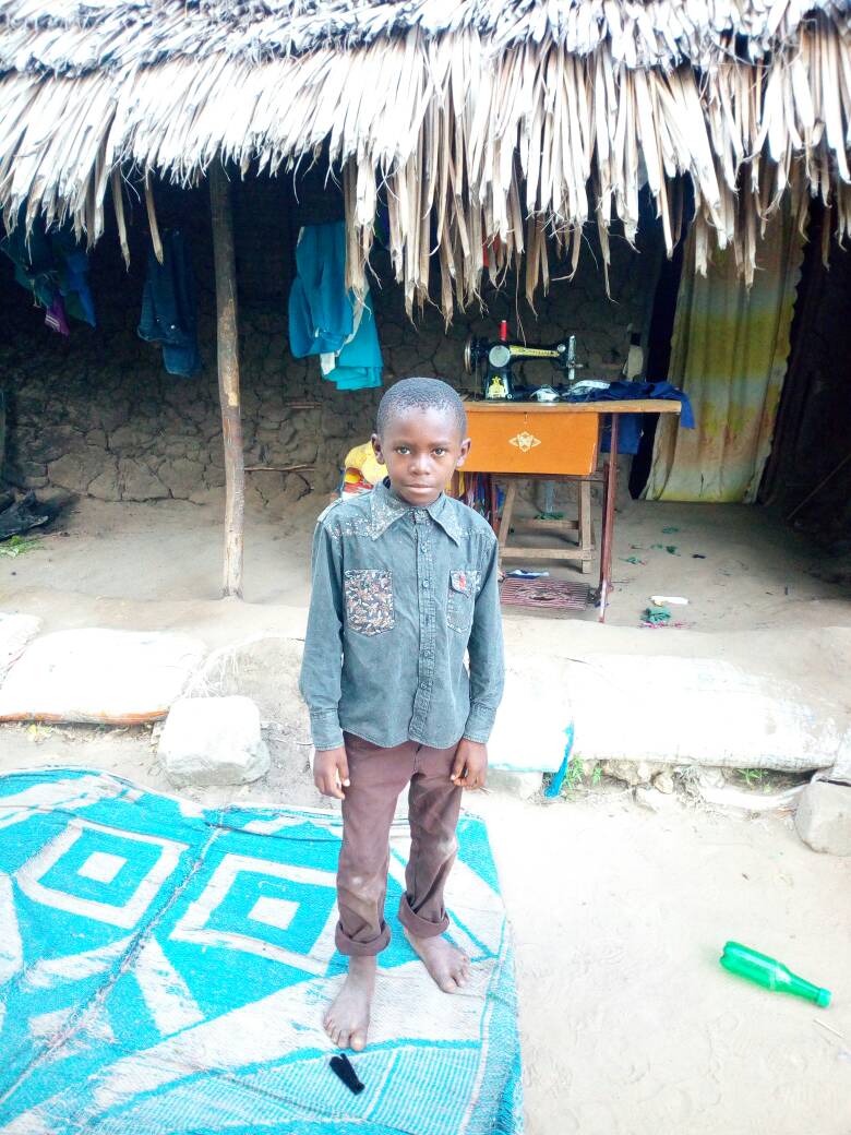 This is Noshadi in front of his home. The sewing machine is treadle powered by his mother, a tailor. 
