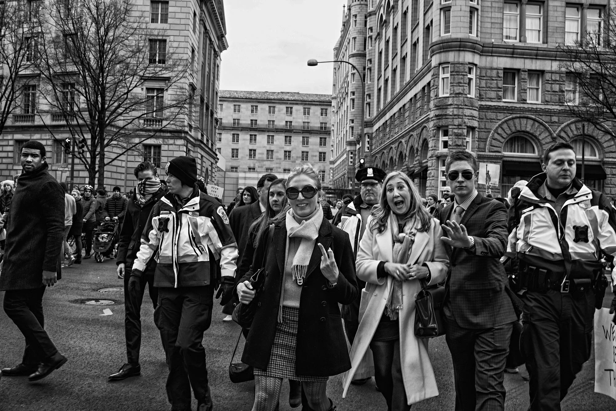 A group of people staying at the Trump Hotel are escorted past protesters after President Trump's executive order banning people from seven countries from entering the United States, on January 29, 2017.