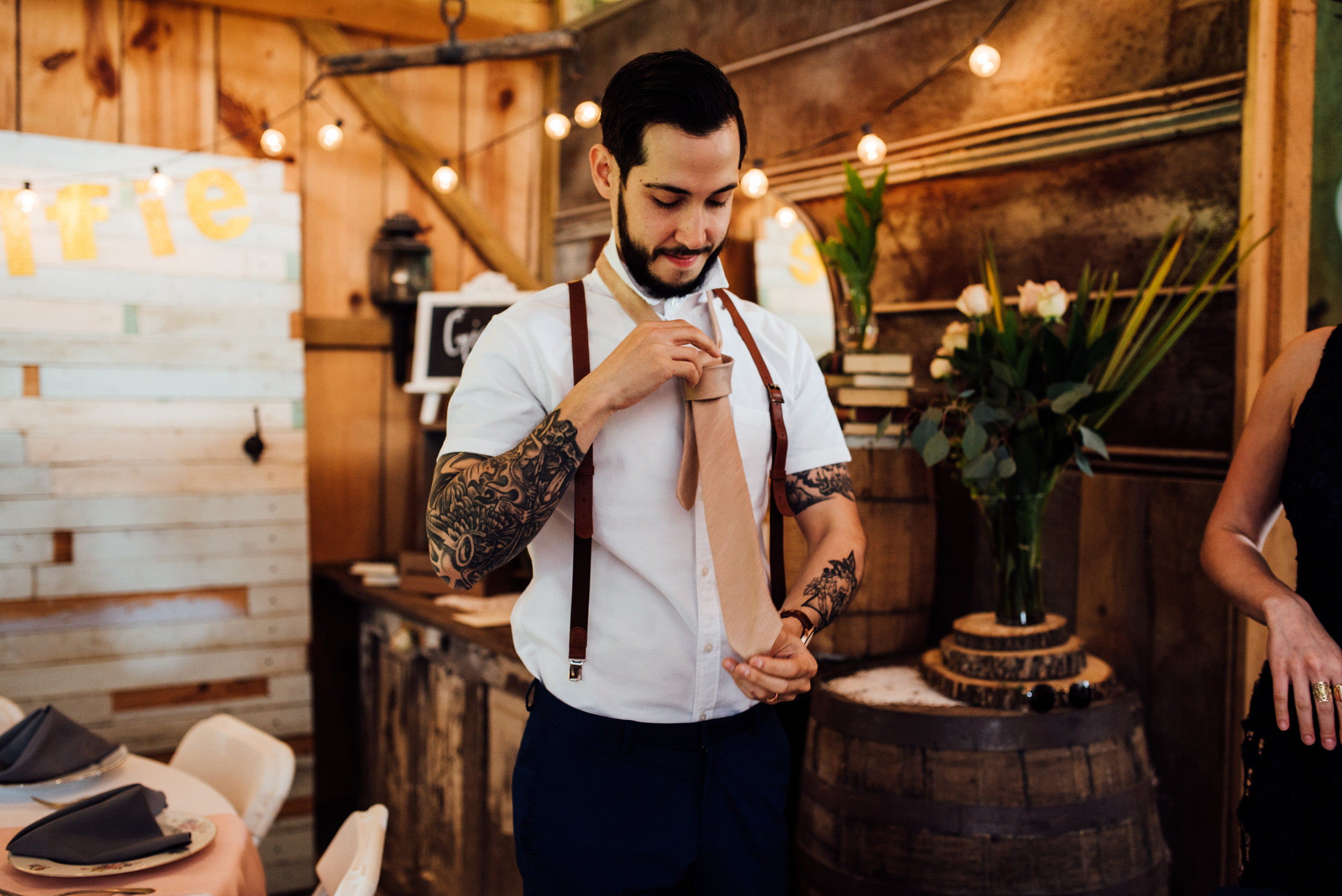 tattooed groom puts on tie
