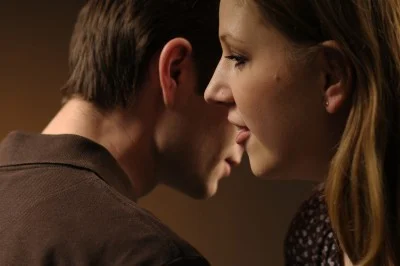Woman whispering in her boyfriend's ear
