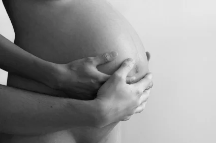 Pregnant woman with her hands and her partner's hands on her belly