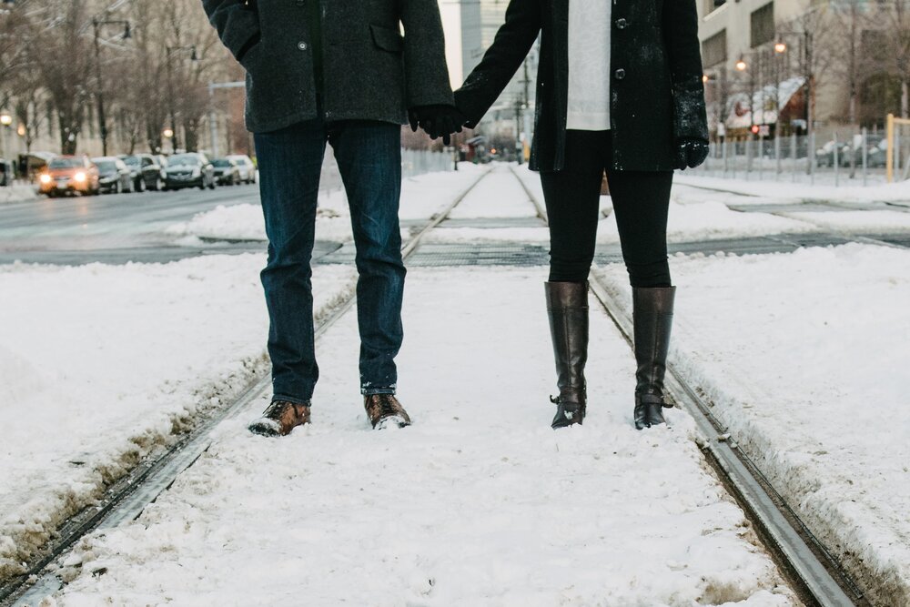 Couple holding hands in winter. Snow on the streets.