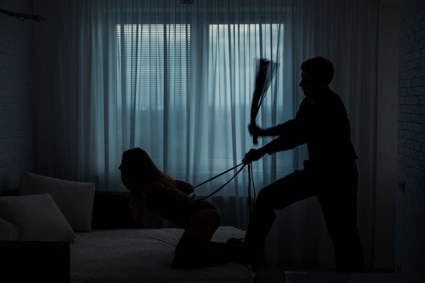 Couple engaged in BDSM. Man flogging female partner.