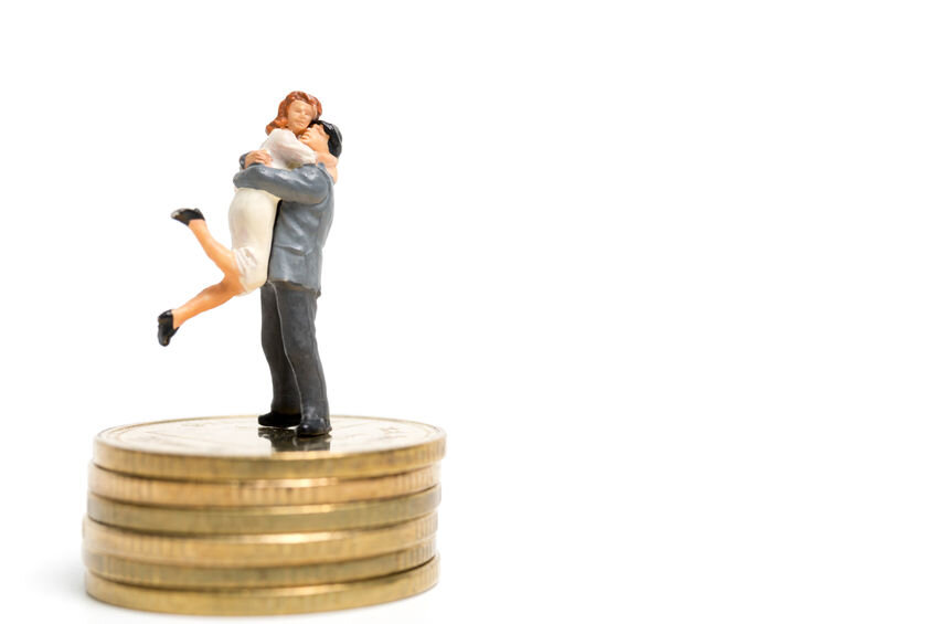 Miniature couple standing on coins. Love economics concept