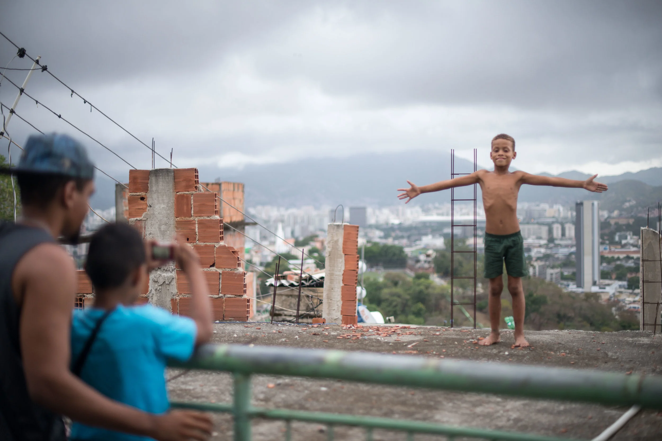 100cameras students taking photos around the city during Snapshot Project Rio, 2017. Douglas watching as Caio captures a moment. 
