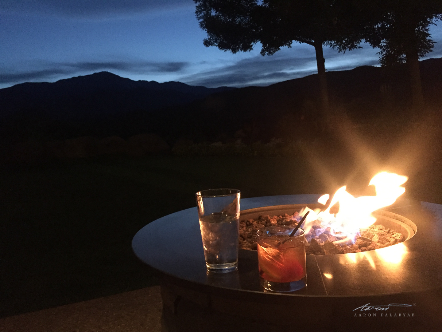 Cold cocktail, warm fire, and the Rocky Mountains at twilight