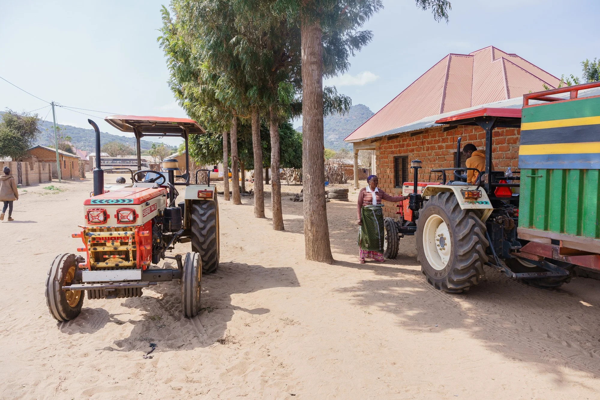 A woman and a man near tractors in a rural setting during a Farm Africa assignment in Babati, Manyara, Tanzania.