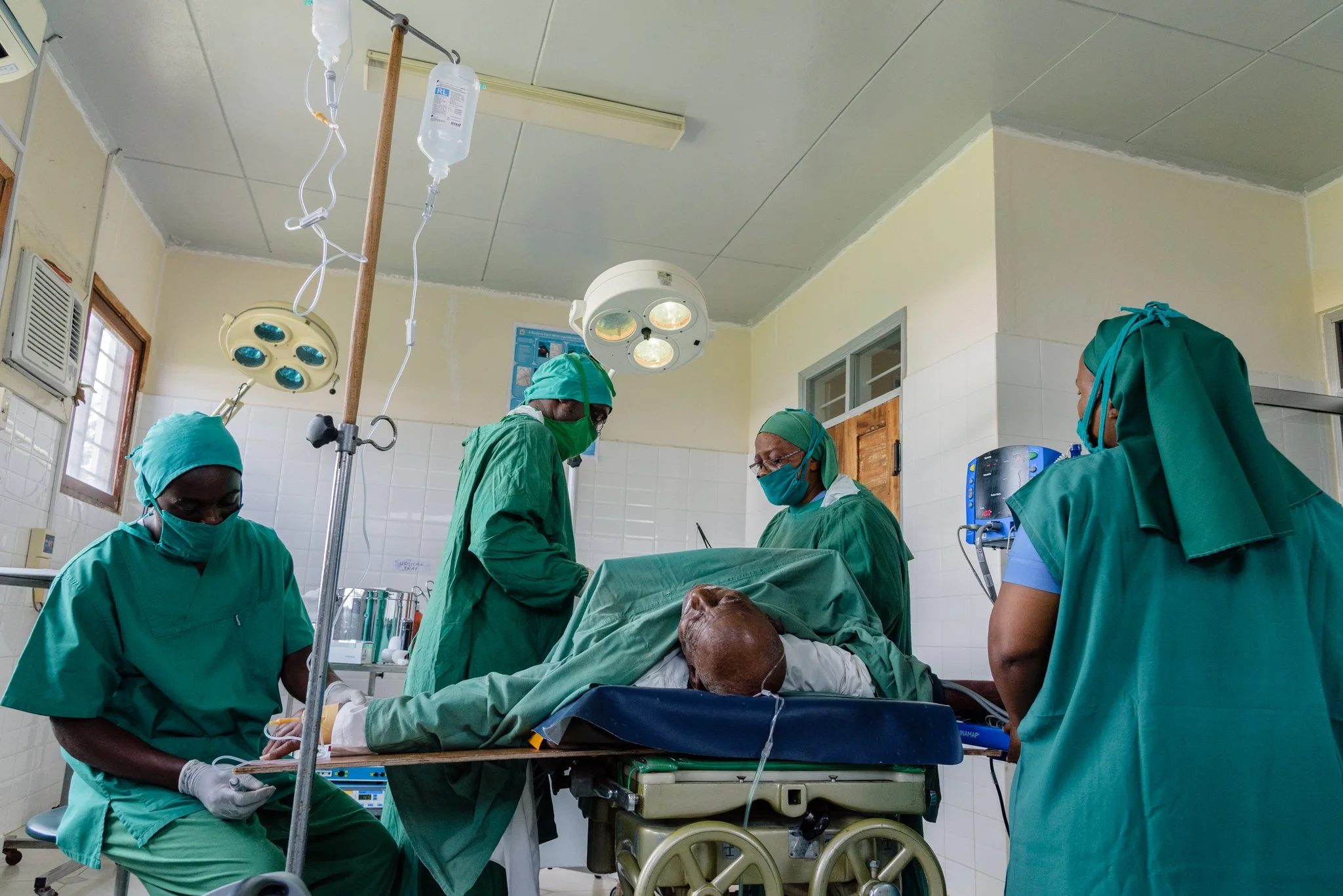 Medical team in surgical masks and scrubs attending to a patient inside an operating room at St. Joseph Health Centre in Kwamndolwa, operated by the Usambara Sisters in Korogwe, Tanga Region, Tanzania.