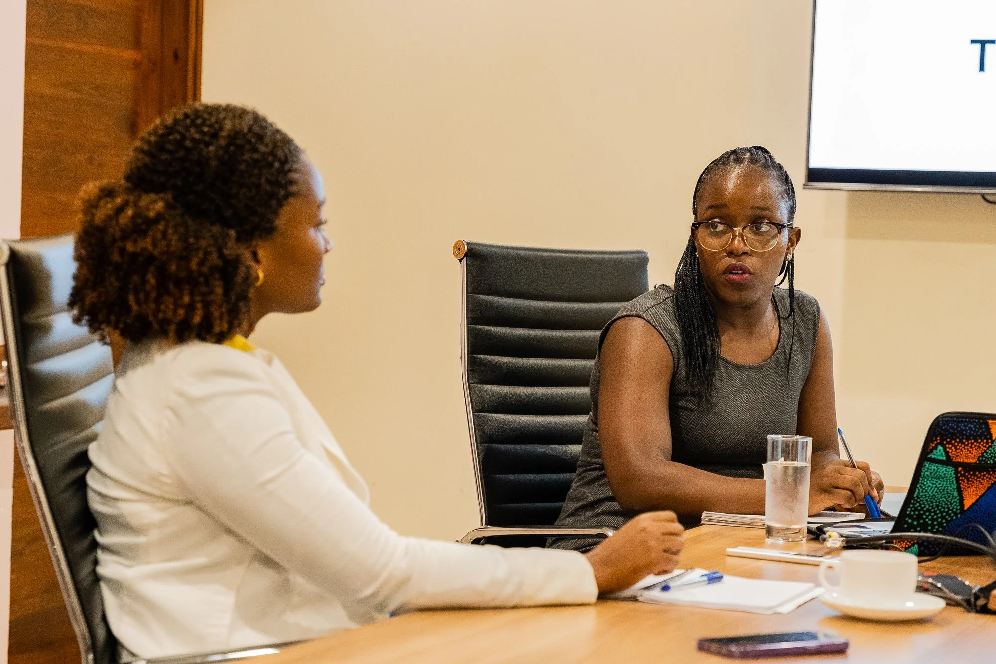 AKFC International Youth Fellowship participant engaged in a one-on-one discussion with a colleague during a workshop session at Aga Khan Hospital, Dar es Salaam, Tanzania.