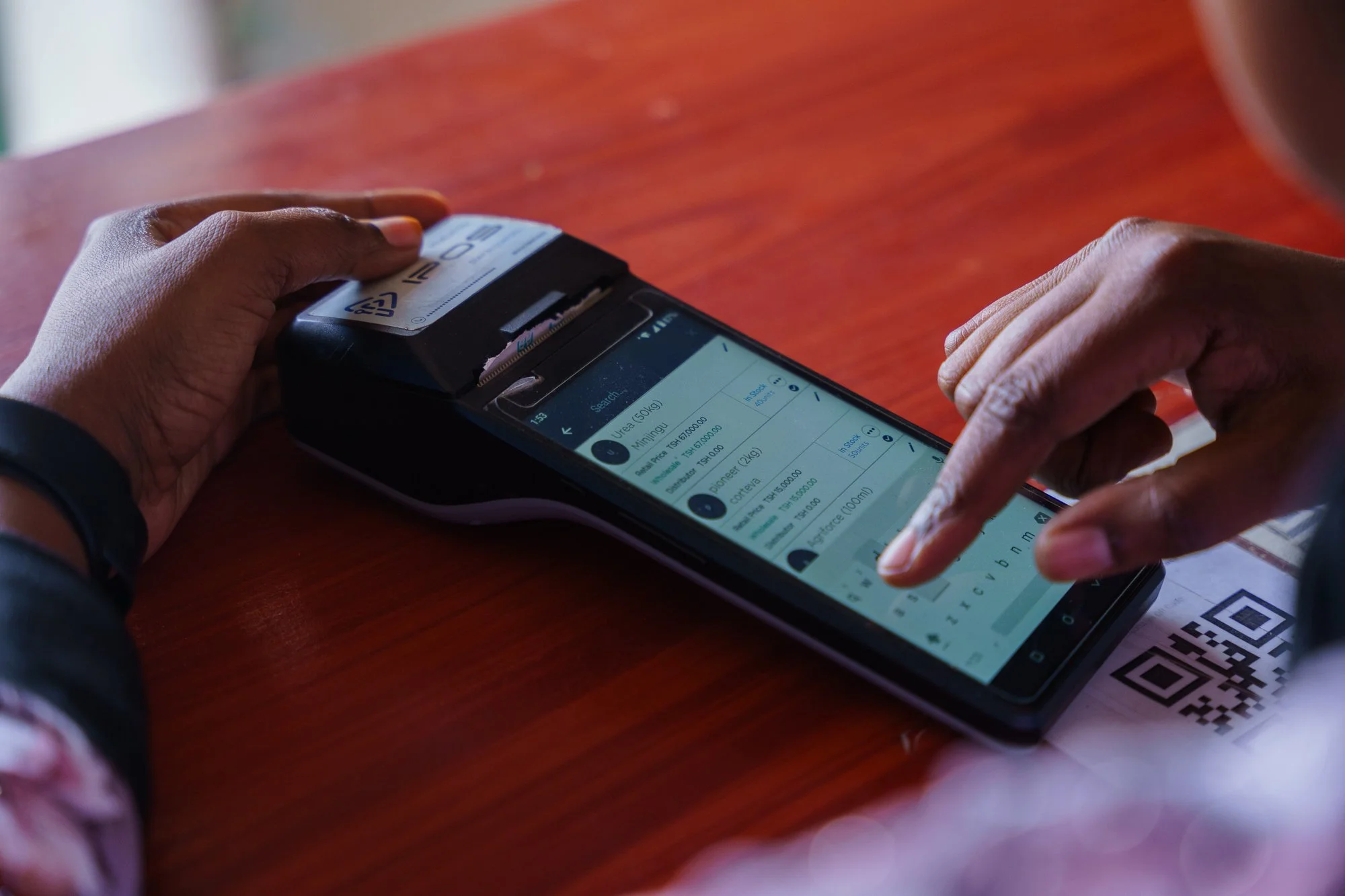 Close-up of a point-of-sale machine in use during a transaction at an agro-input shop in Babati, Manyara, Tanzania.