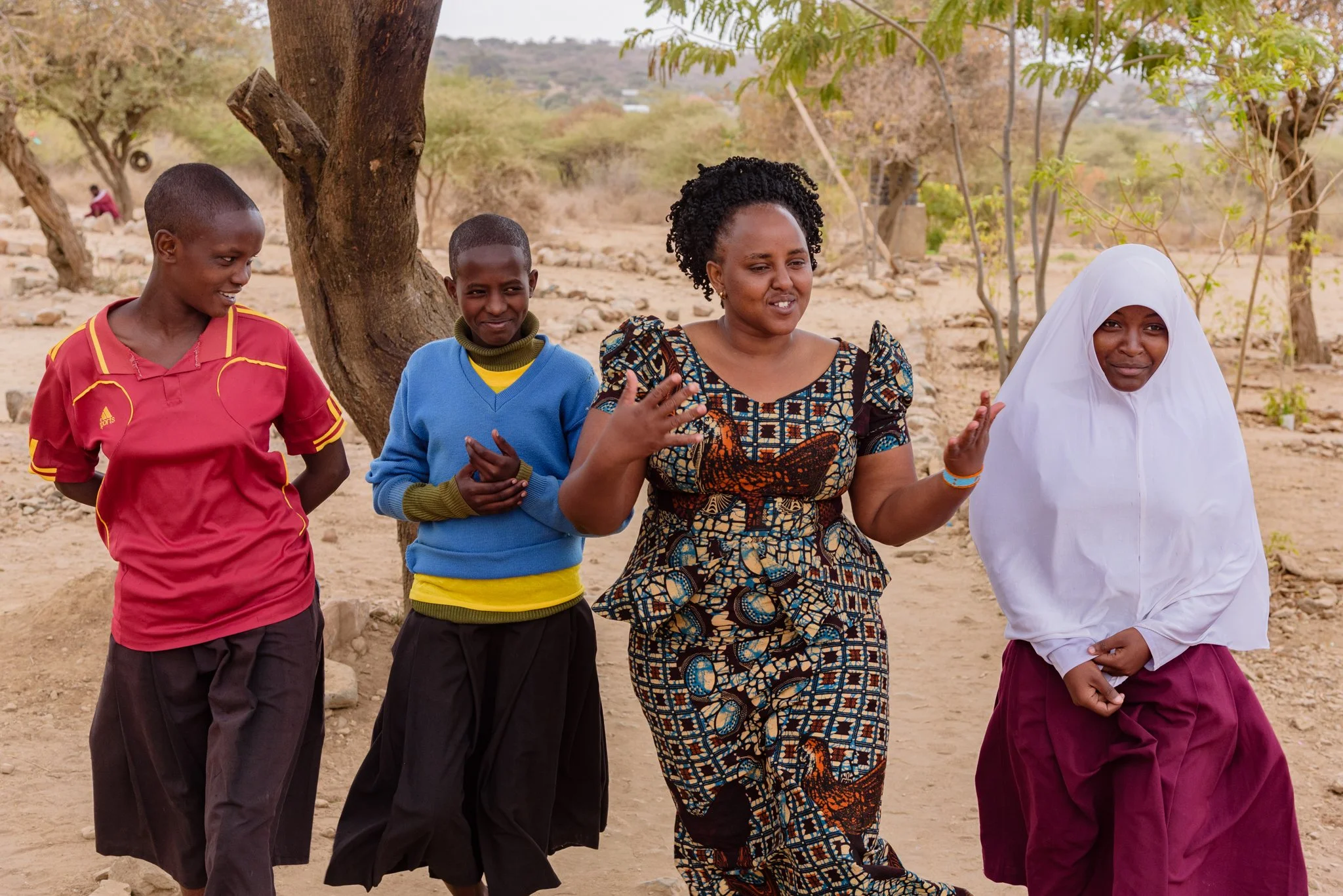 Malala Fund Education Champion walking and interacting with three Tanzanian secondary schoolgirls outdoors in Arusha, Tanzania