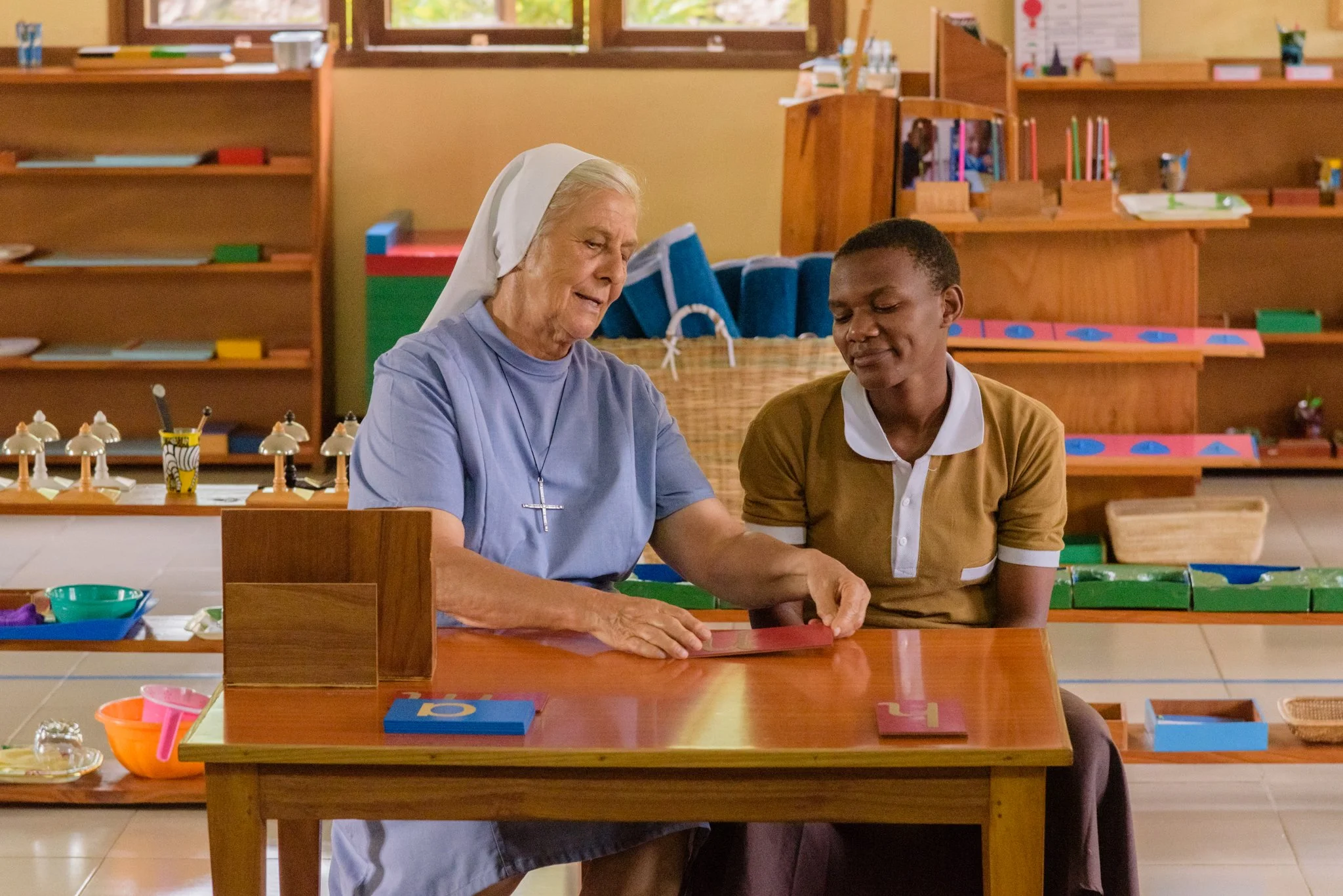 Nun instructor at a teacher training centre demonstrating Montessori teaching methods by using letter-based learning tools while guiding a trainee teacher during a lesson in Mwanza, Tanzania.