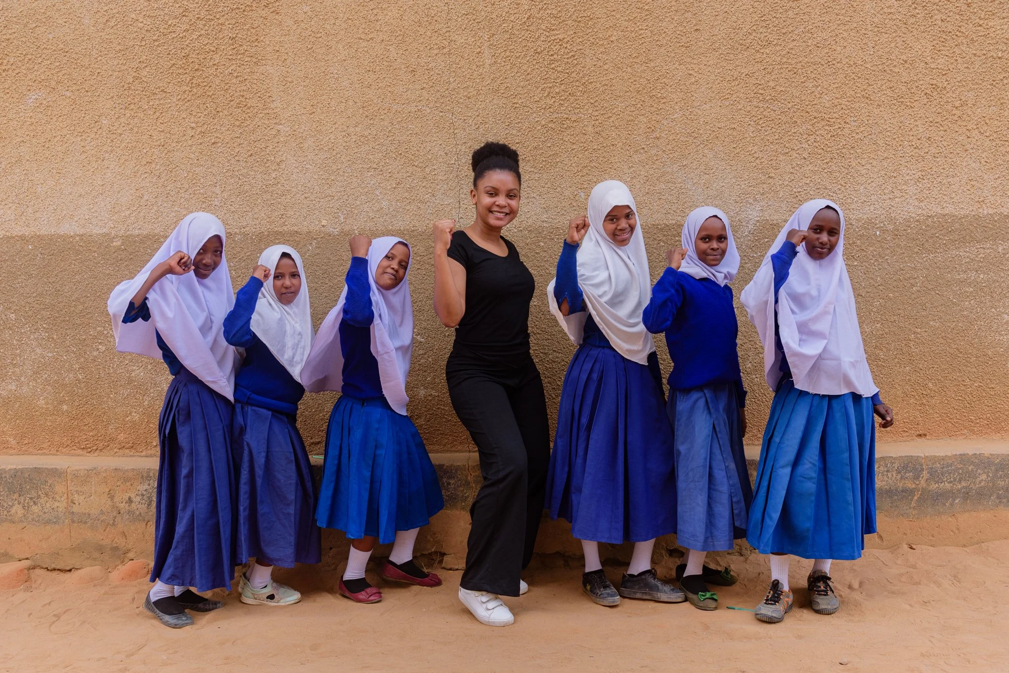Six Tanzanian schoolgirls in blue-and-white uniforms with Malala Fund education champion in Dodoma, Tanzania.