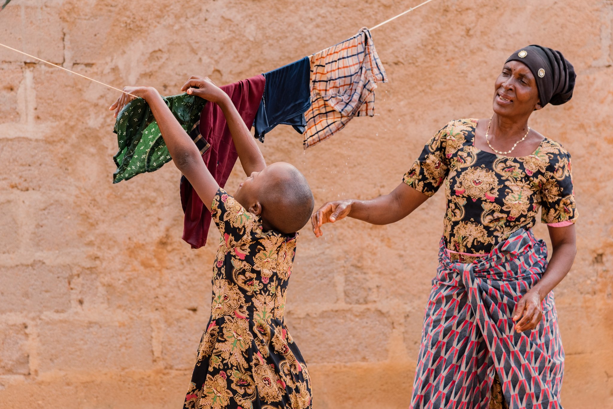 Caregiver interacting with a child outdoors in Tanzania, showing everyday family life within an inclusive education support programme by Leonard Cheshire.