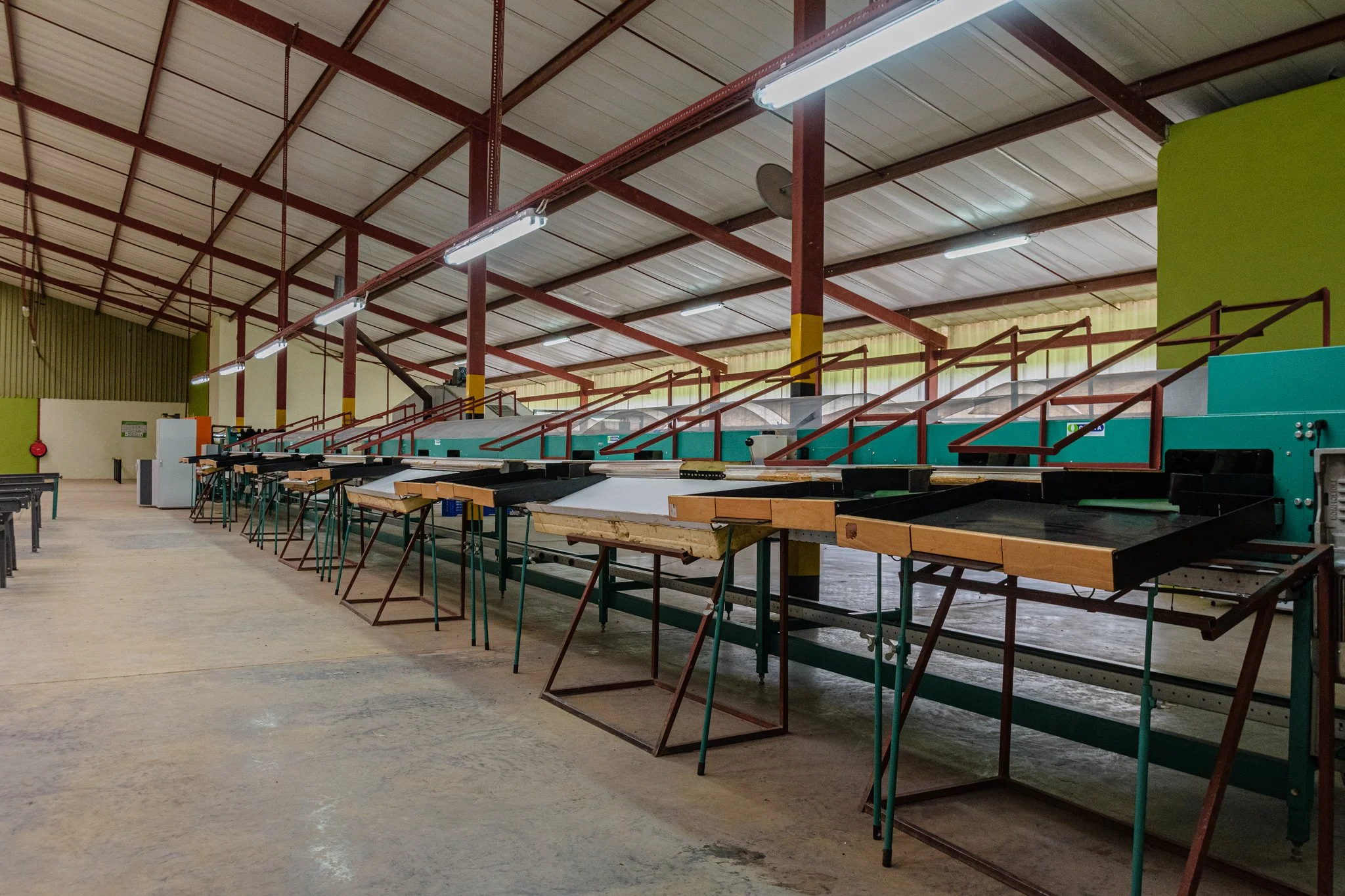 Empty industrial workspace with multiple desks and machinery along a wall in a warehouse. In Mbeya, Tanzania.