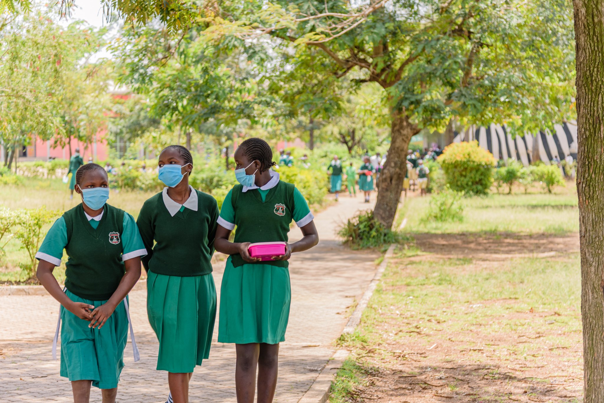 Schoolgirls walking through school grounds in Kenya, representing access to inclusive education supported by Leonard Cheshire.