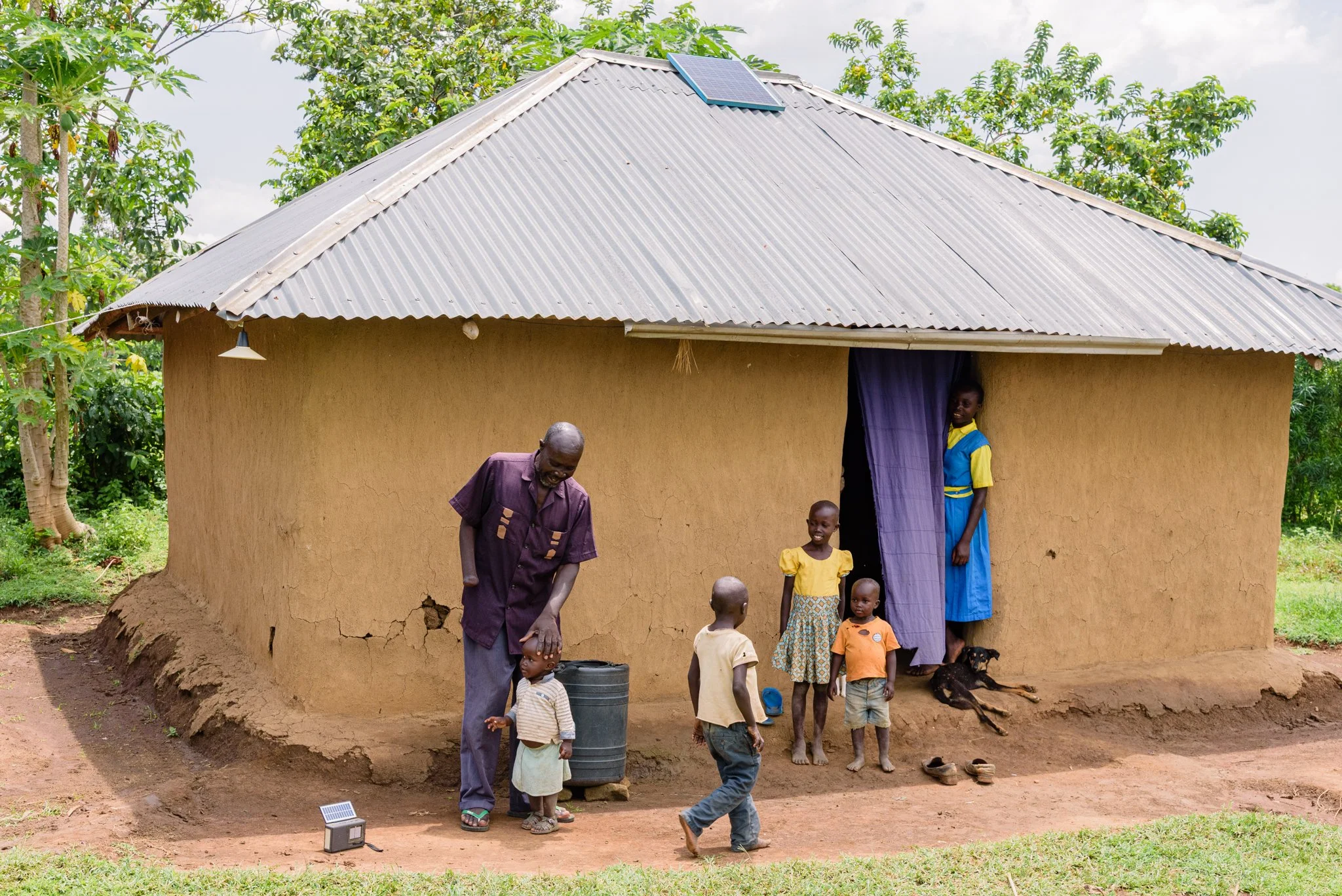 Family outside their home in Kenya, illustrating the living environment connected to Leonard Cheshire’s inclusive education work.