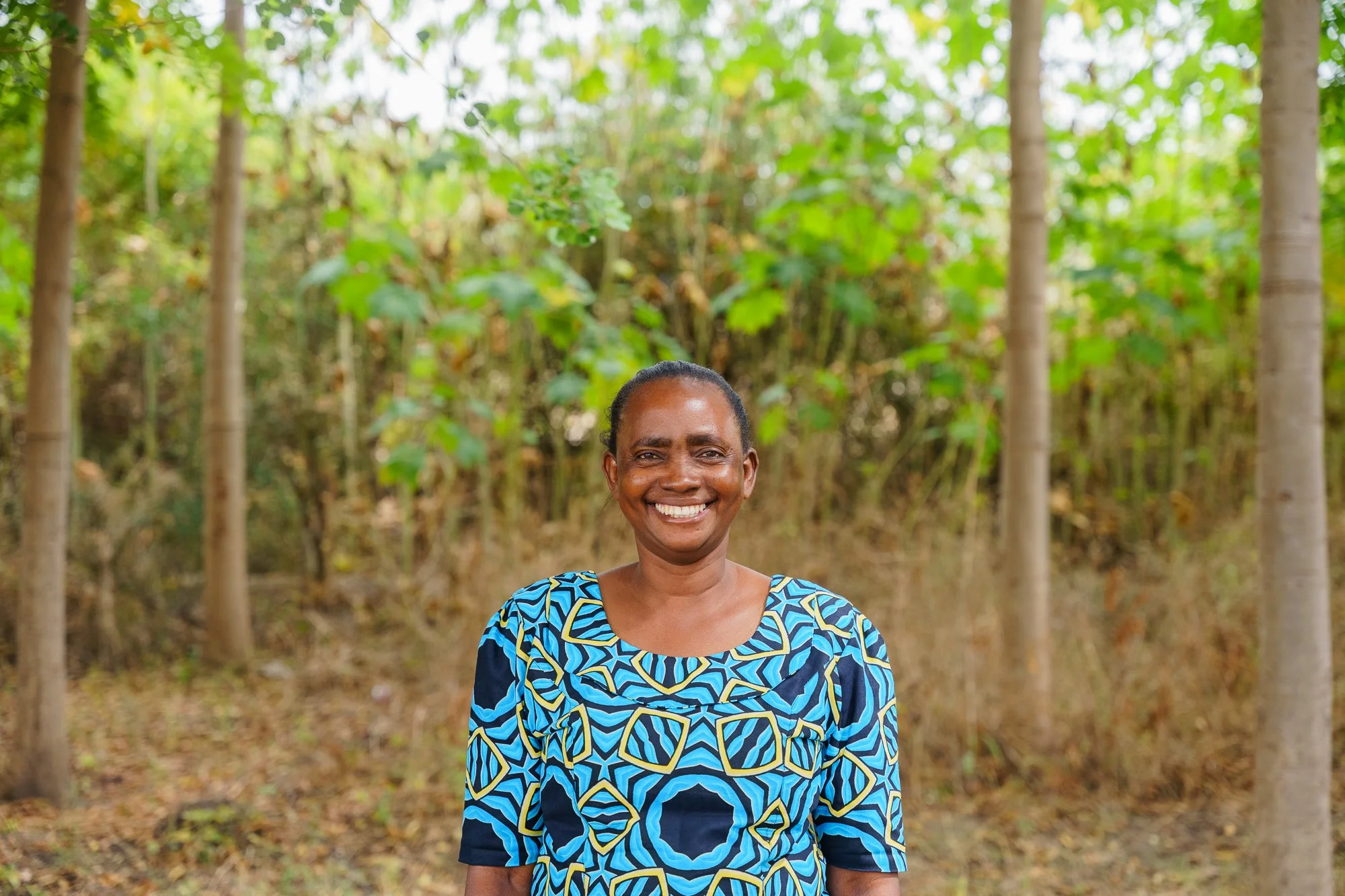 Female farmer standing confidently in a tree plantation in Babati, Manyara, Tanzania.