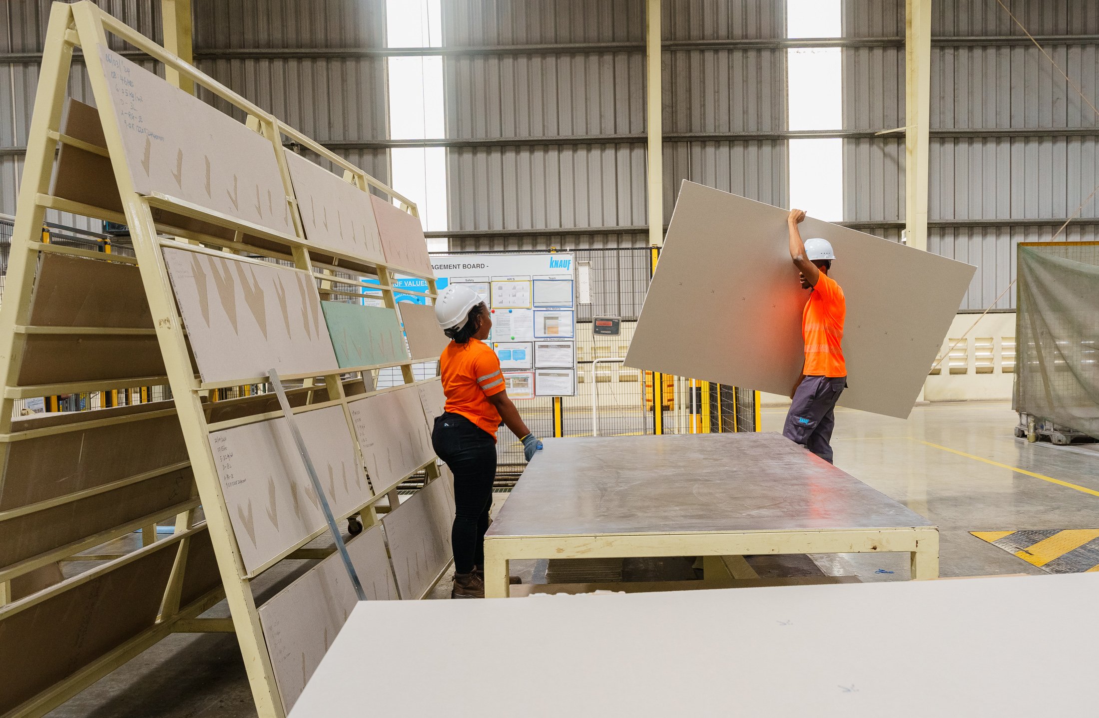 Factory workers moving construction boards inside a modern manufacturing plant in Mkuranga, Tanzania