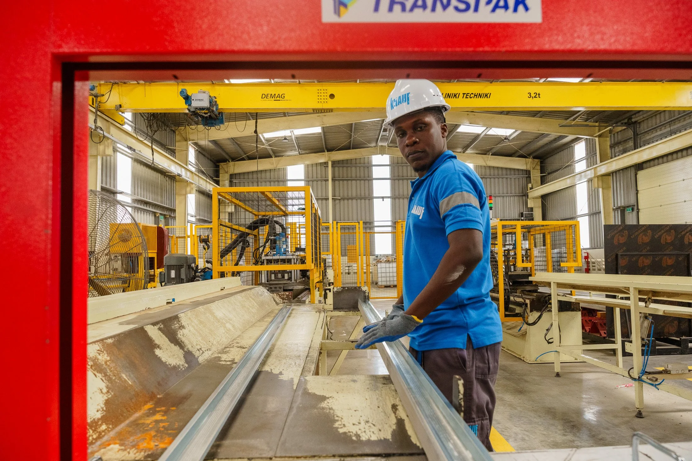 Factory worker standing within an active production area surrounded by industrial machinery