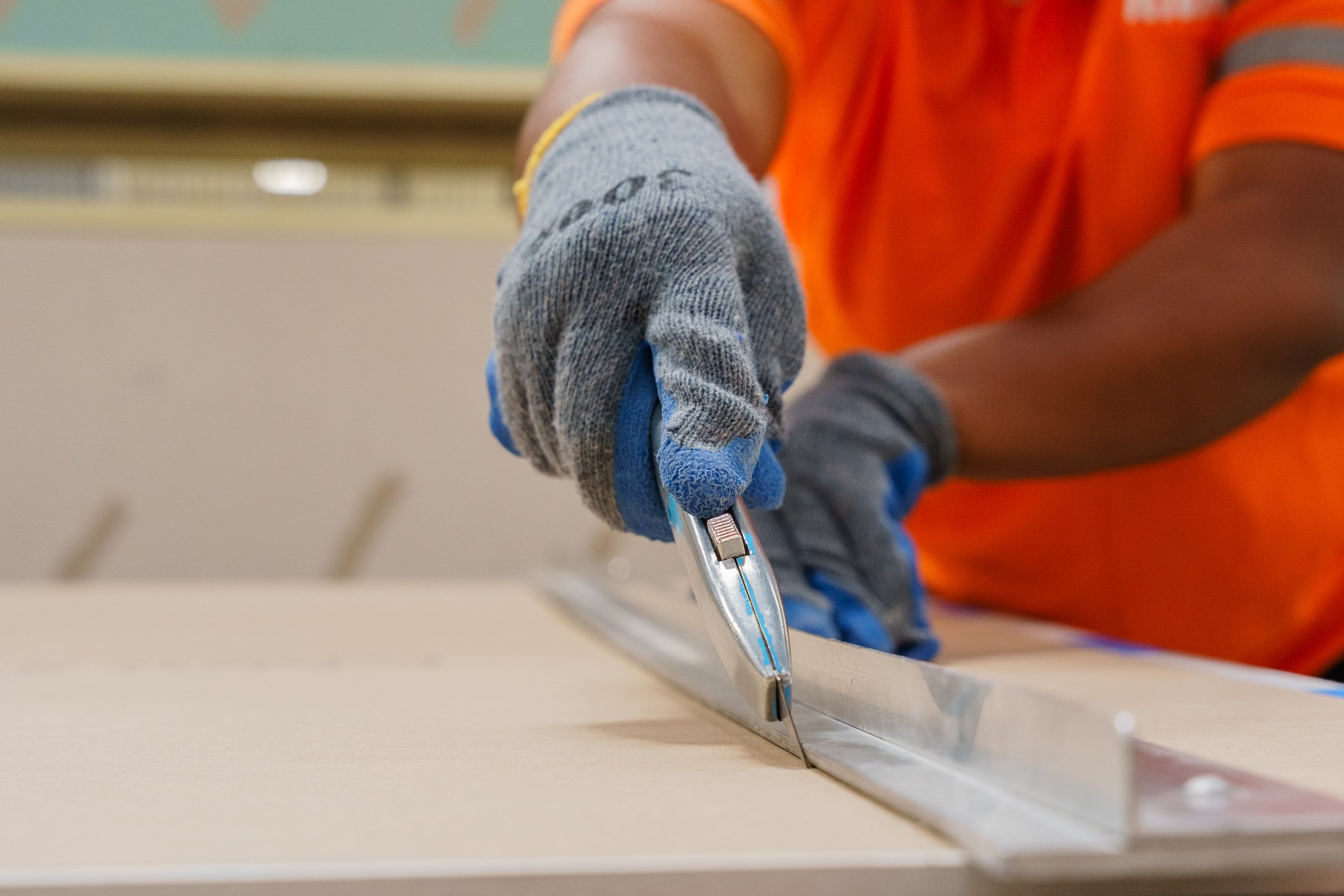 Close-up of a worker’s hands measuring and cutting building material during quality control