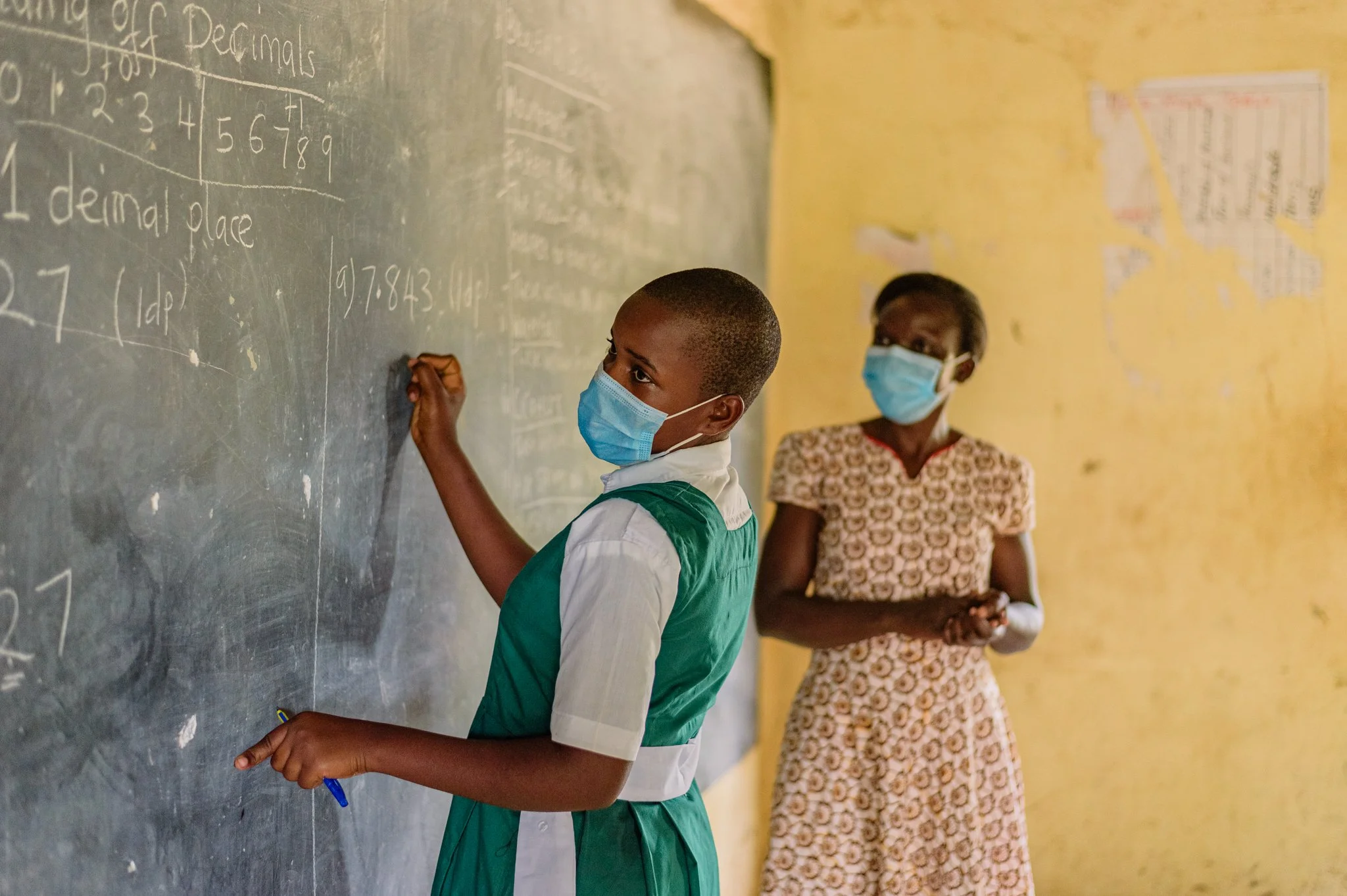 Teacher supporting a student with learning tasks in a Kenyan classroom as image capture during a Leonard Cheshire’s inclusive education project.
