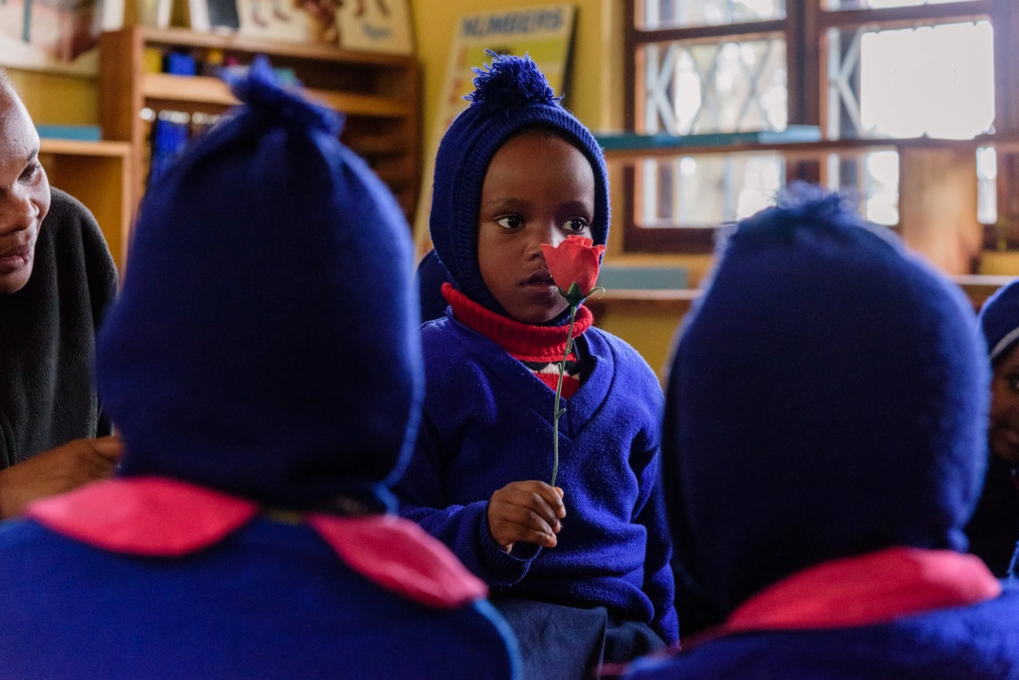 Young Montessori kindergarten student holding a flower during a colour-learning activity in Lushoto, Tanga Region, Tanzania.