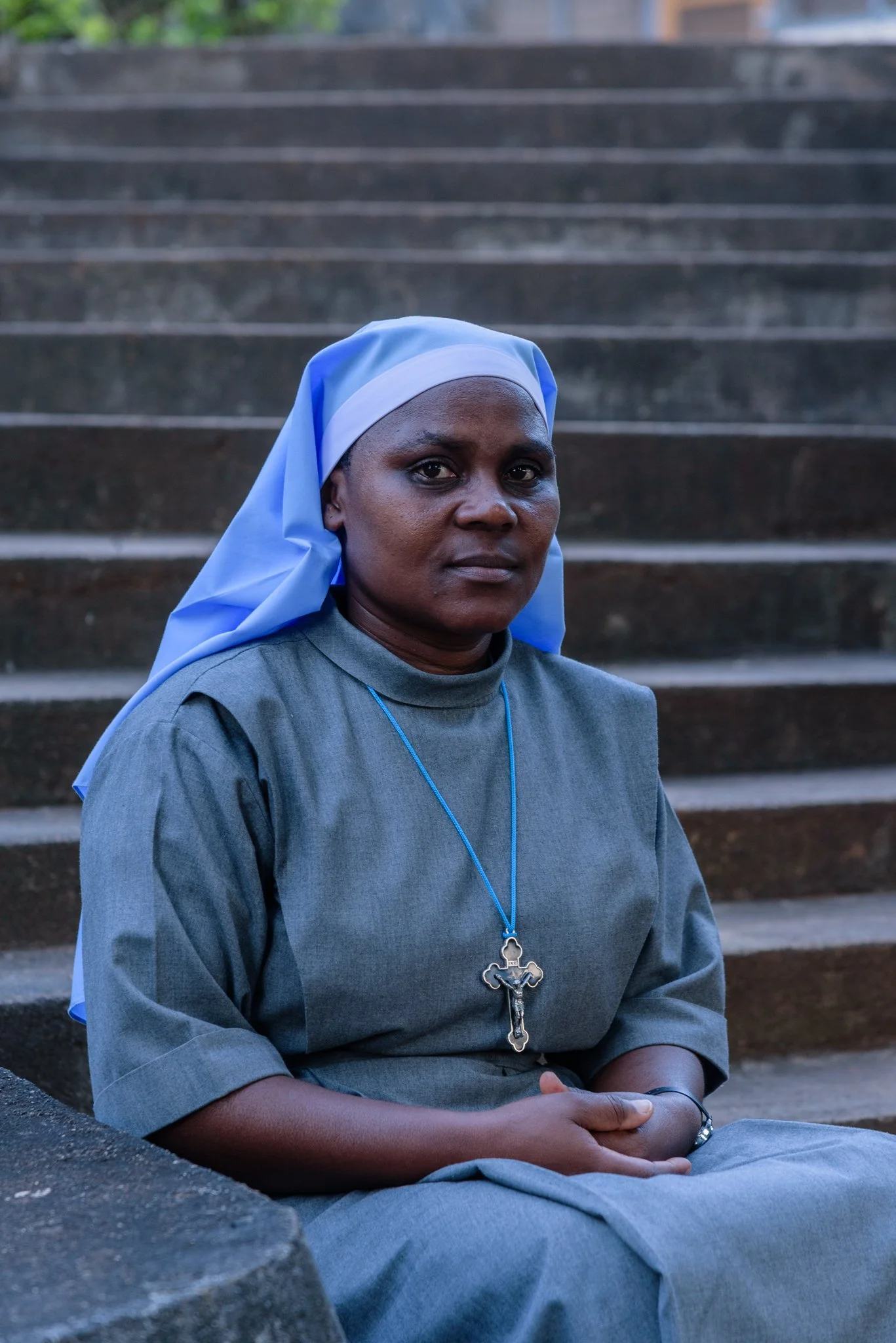 Portrait of a Catholic nun seated on steps outdoors at the Usambara Sisters Convent in Korogwe, Tanzania.