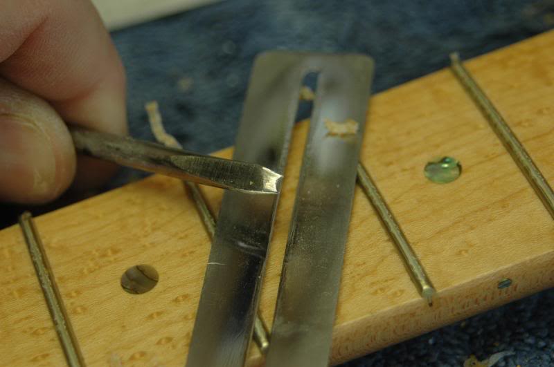 First thing, I remove the lacquer build-up from the frets. The tool is a screwdriver I reshaped the tip to cradle the fret, as I scrape the soft lacquer from the fret. 