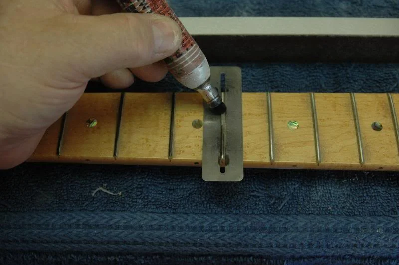 Now, I recommend taking a marker, and coloring each fret. This makes seeing what you are doing much easier, and you can fine tune your truss rod leveling. Place your leveling tool on the fingerboard and give it a shove, remove and check the marked frets. If the end frets have been scraped and the middle ones not, then tighten the truss rod a touch and repeat. Continue until the frets toward the center of the fingerboard are being “hit” too. Now re-coat all the frets with the marker, and recheck. If the majority of the frets show exposed metal from the fret leveling tool, you are ready to rock.