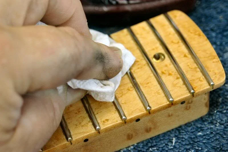 I do the same on the heel, then re mask and do the edge of the heel. Once that’s done I begin polishing the frets, I use several methods, depending on the neck, here I’m going over each with a cleaner car wax. It’s perfect because it will polish the fret and clean any residue from the base of the fret.